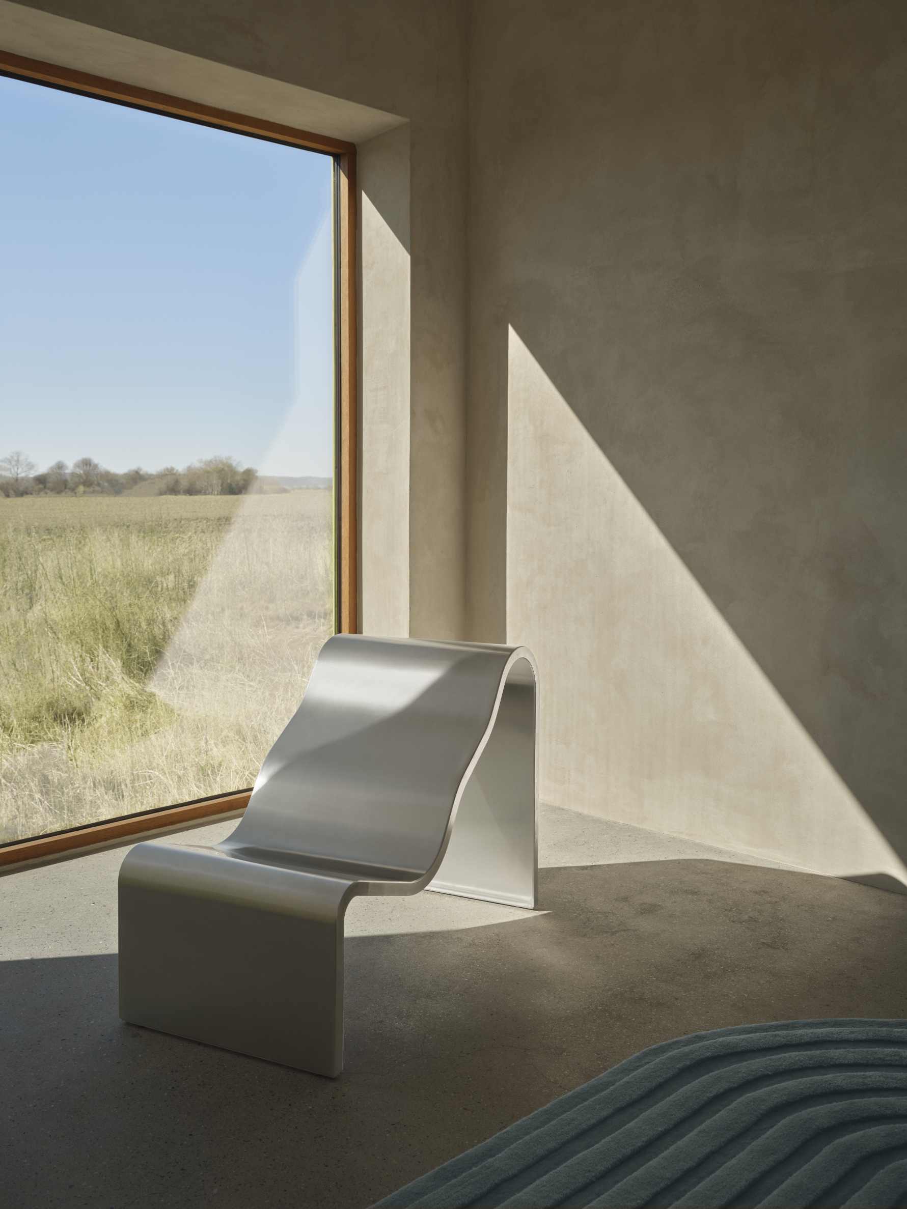Helle Dream Bench Bank von Muuto im minimalistischen Raum mit Fenster und Feldblick.