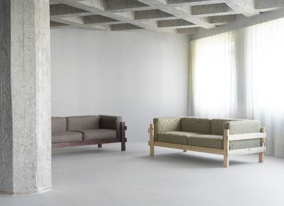 Zwei Kube Sofas von Normann Copenhagen in minimalistischem Raum mit Betonpfeiler und Tageslicht.