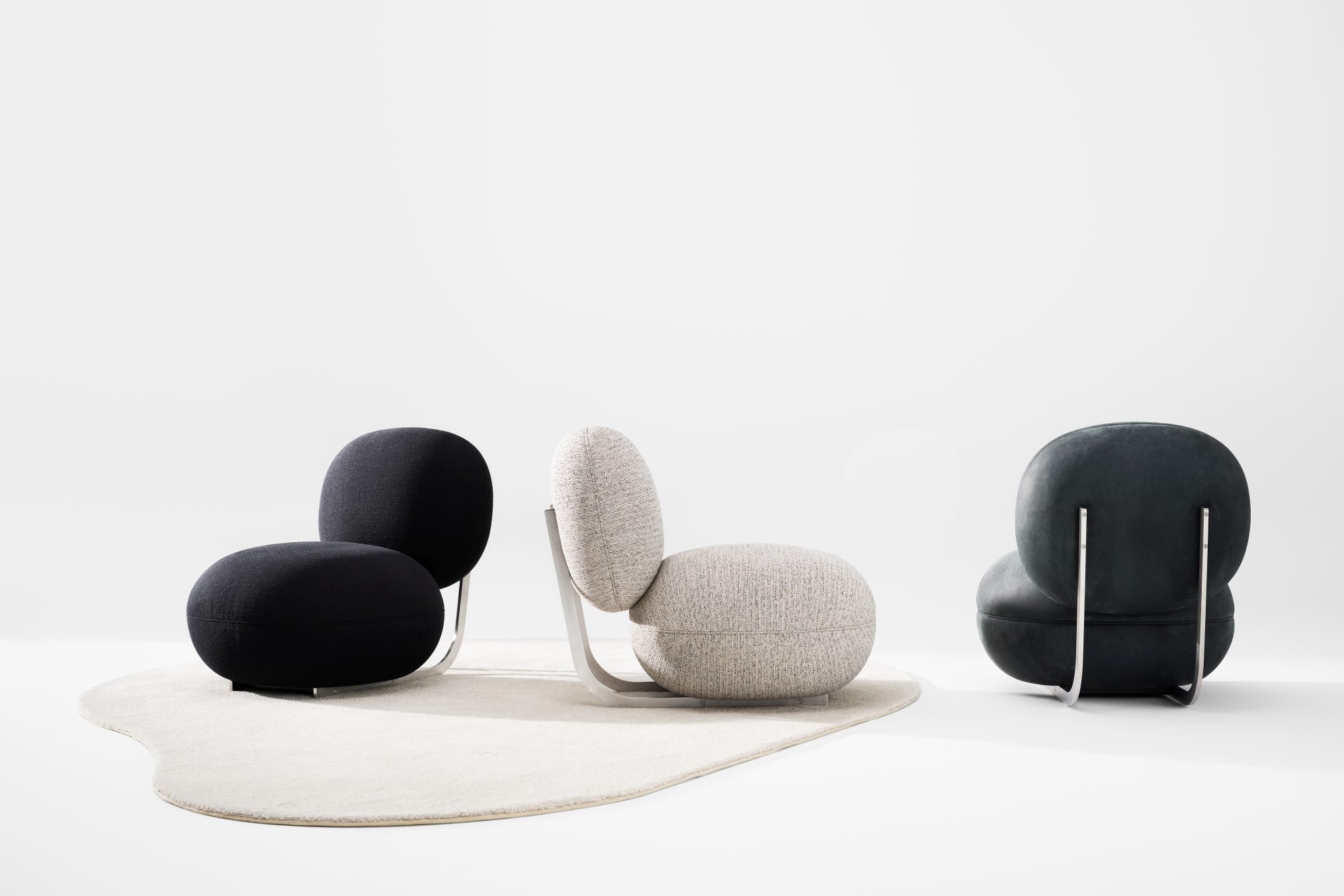 Drei Copper Lounge Sessel von NORR11 in Schwarz, Grau und Anthrazit mit Edelstahlgestell auf Teppich.