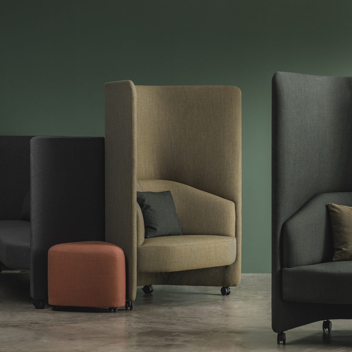 In Out Office Loungesessel mit hohem Panel in Beige, Grau und Schwarz, ergänzt durch einen orangefarbenen Hocker.
