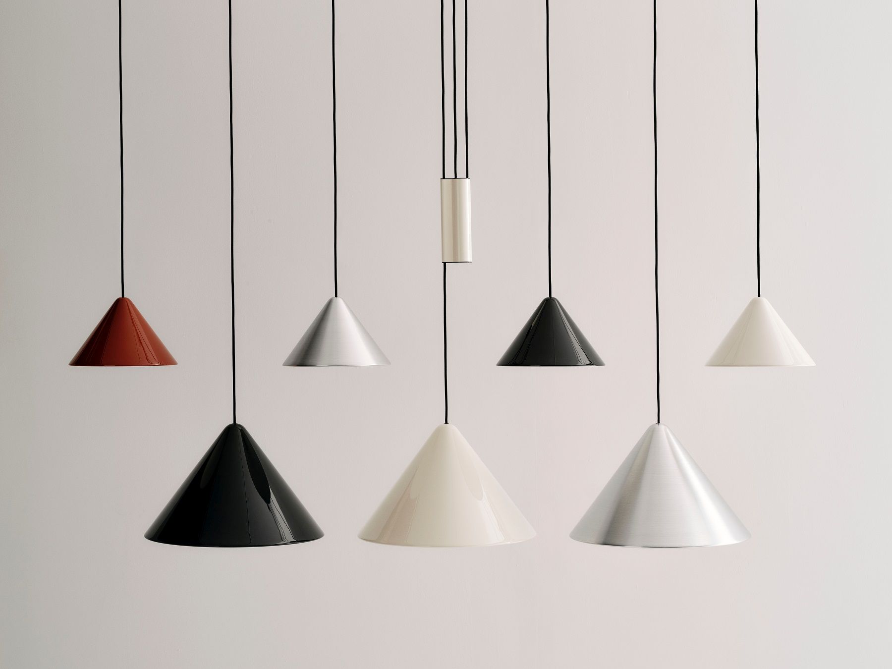 Mehrere Compass Pendant Pendelleuchten von Hay in Aluminium gebürstet, schwarz, weiß und rot hängen von der Decke.
