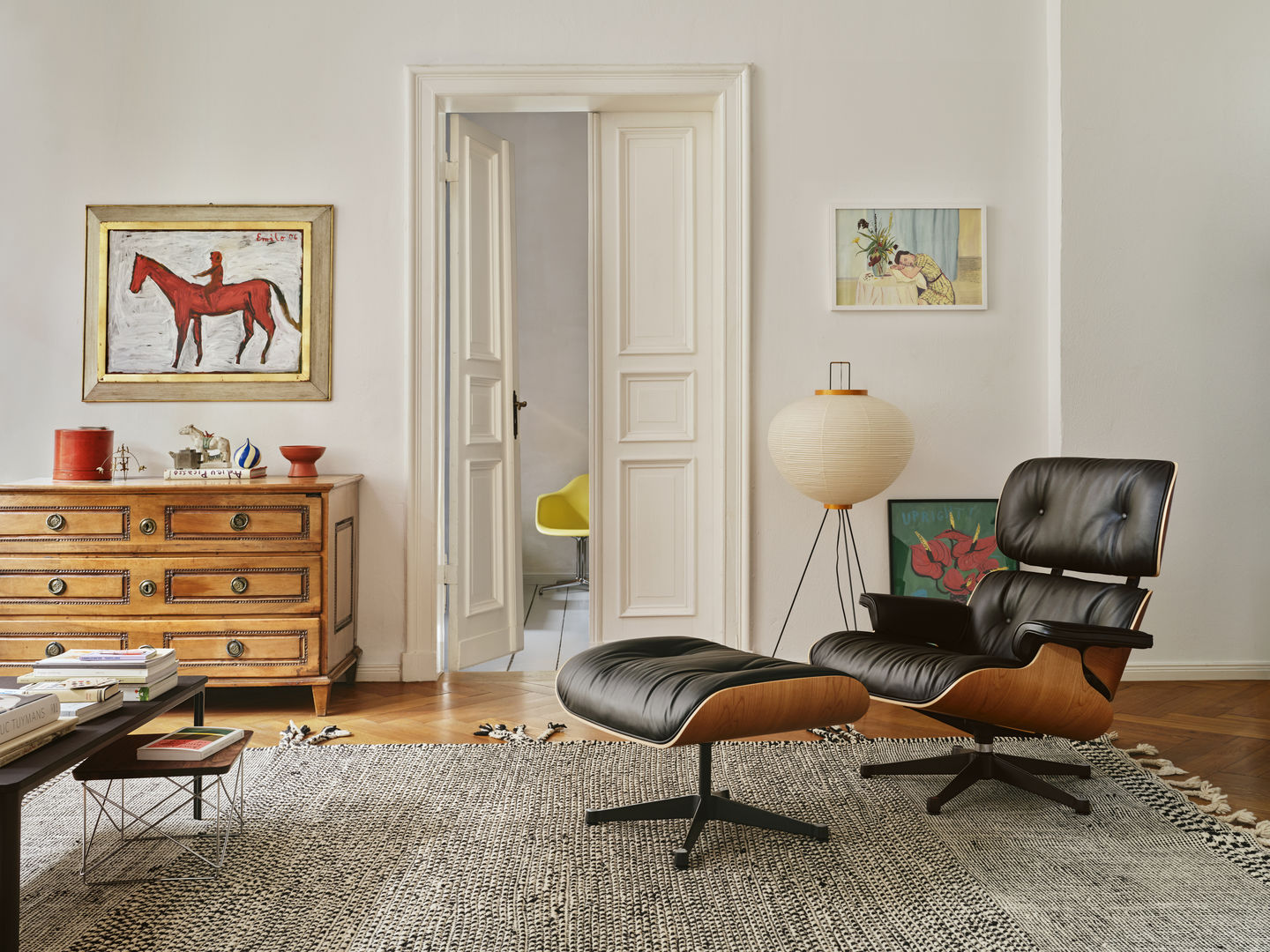 Eames Lounge Chair mit Ottoman in schwarzem Leder und Holzfurnier in stilvollem Wohnzimmer.