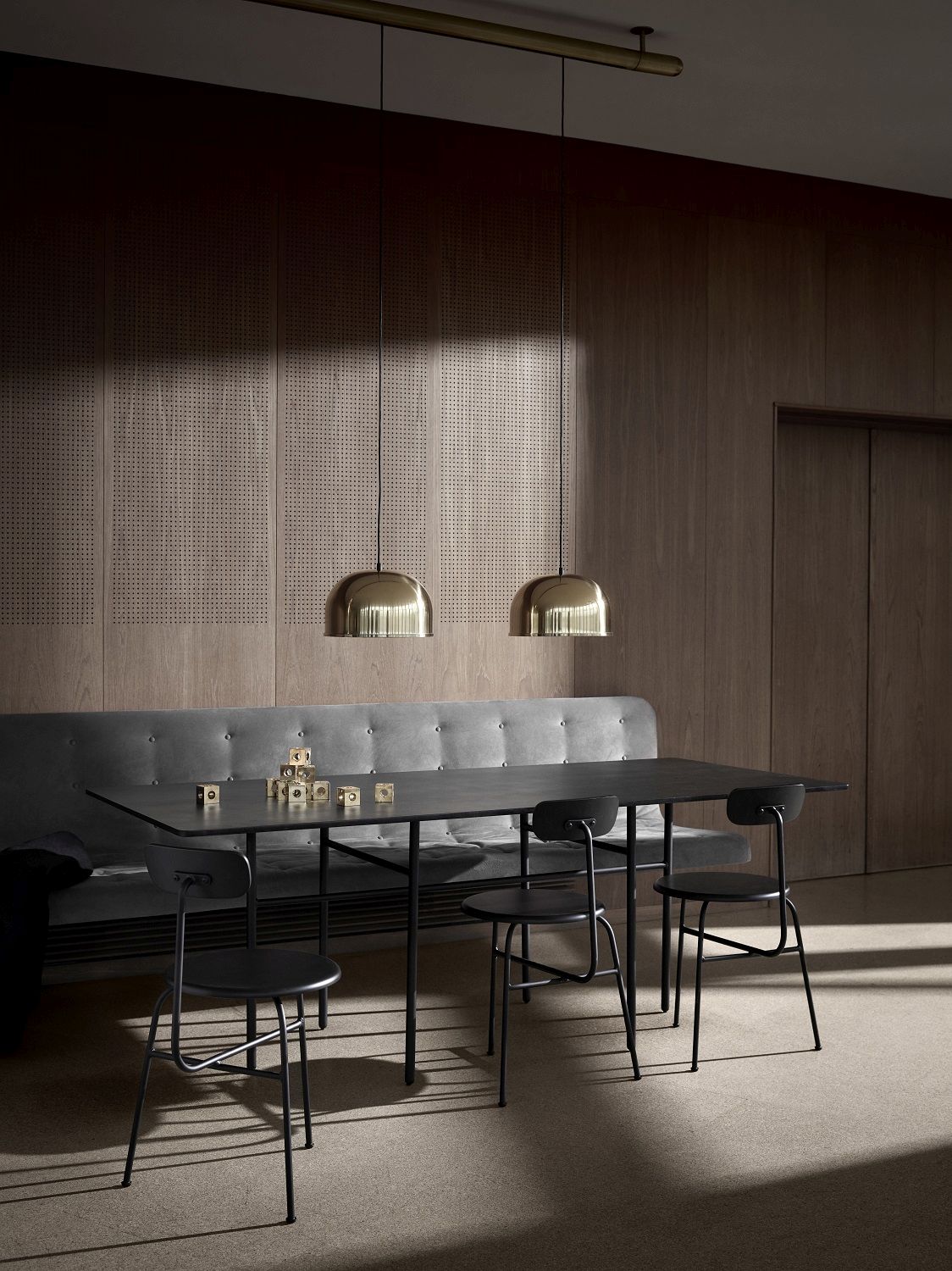 Esszimmer mit schwarzem Tisch, grauer Bank und vier schwarzen Afteroom Dining Chairs von Audo Copenhagen.