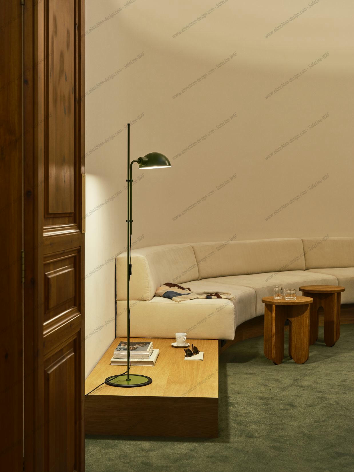 Moosgrüne Funiculí Stehleuchte von Marset im Wohnzimmer mit Sofa und Holztischen.