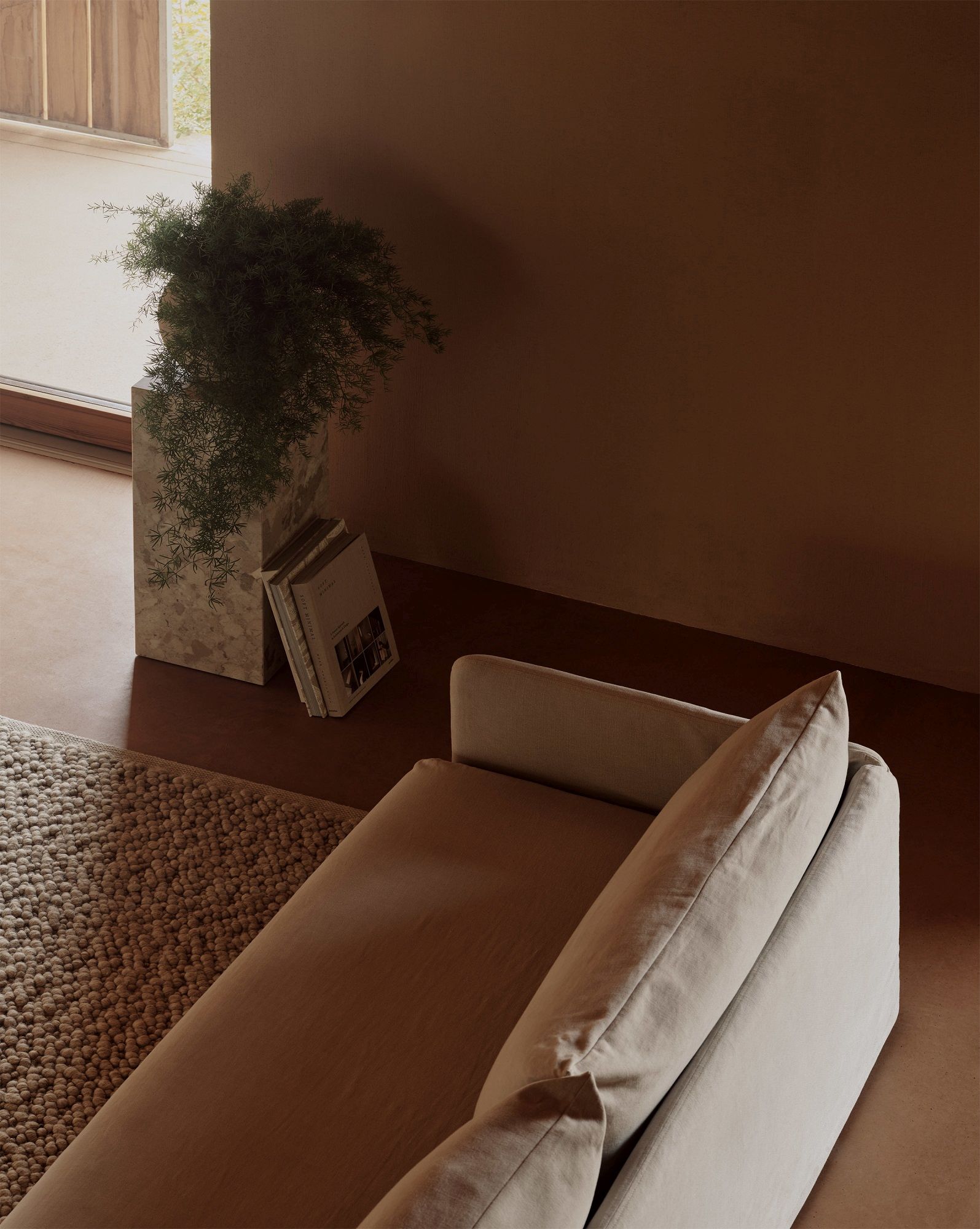 Beige Offset Sofa von Audo Copenhagen, einladendes Wohnzimmerambiente mit Teppich und Zimmerpflanze.