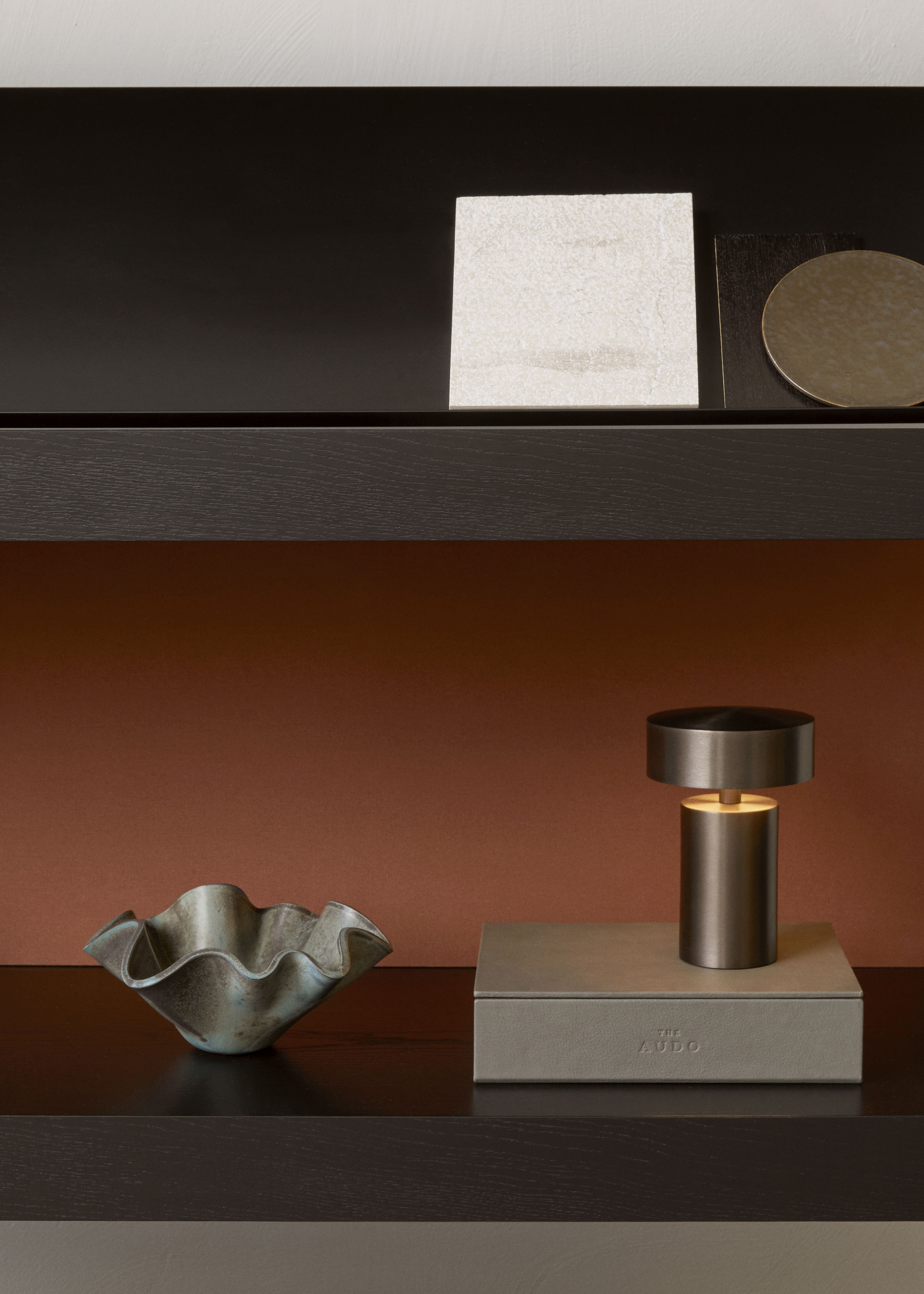 Detailaufnahme eines Audo Copenhagen Regals mit dekorativen Elementen wie Lampe und Schale.
