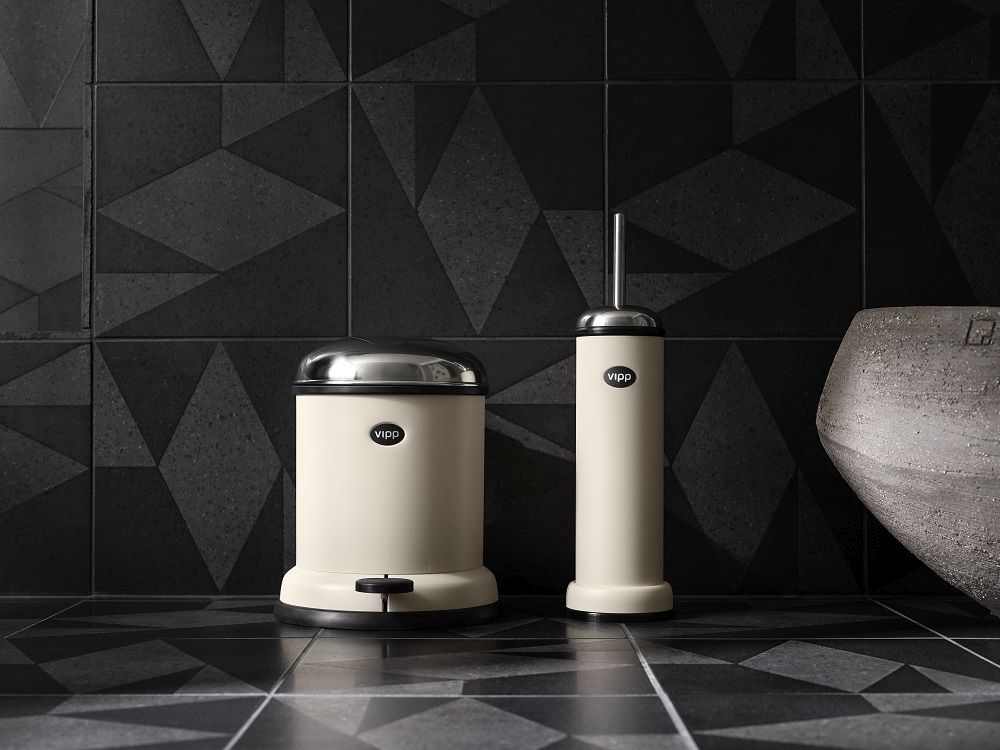 Beiger Vipp Treteimer 4 Liter und passende WC-Bürste im modernen Badezimmer mit dunklen Fliesen.