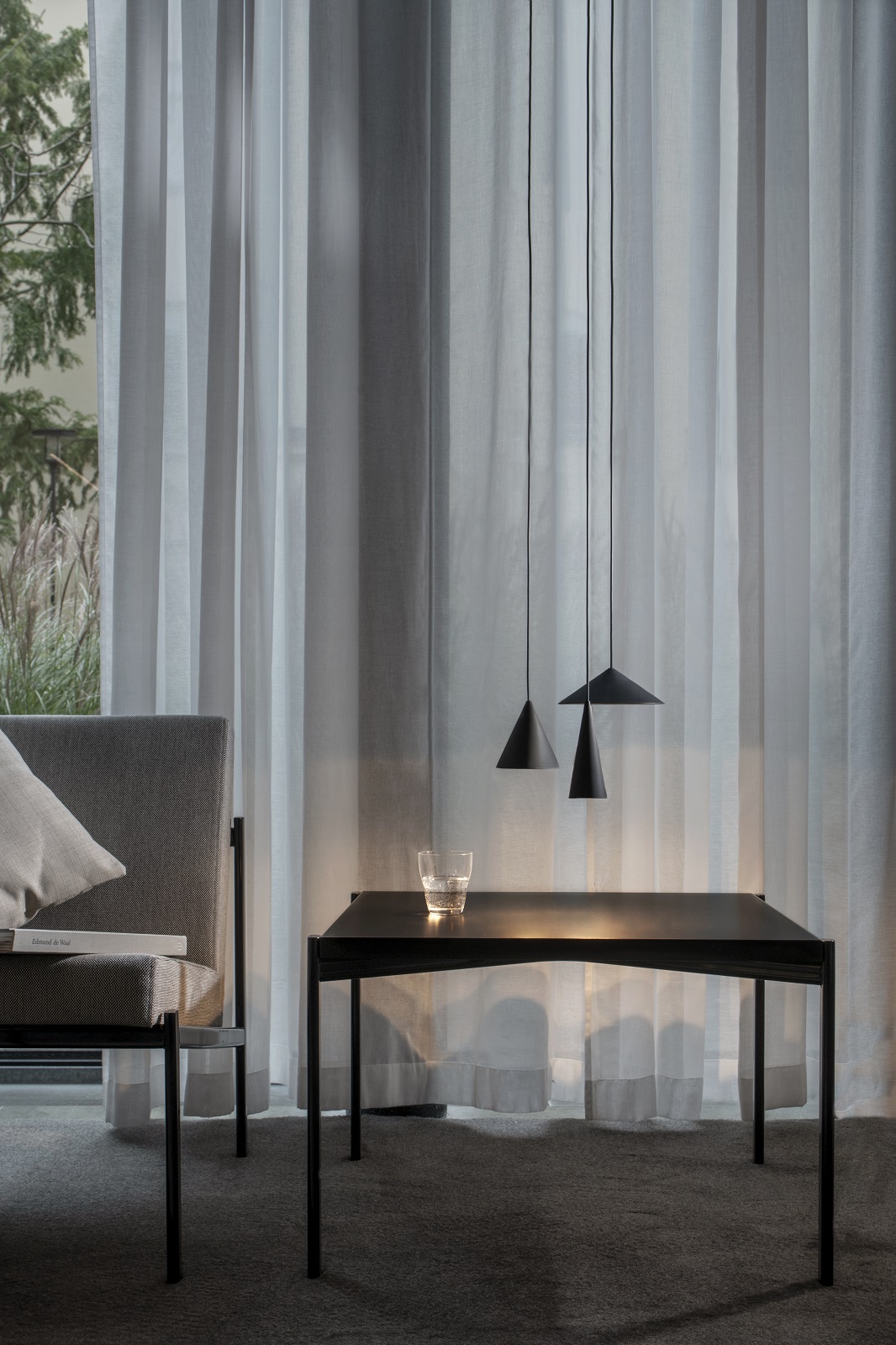 Drei schwarze w201 S3 Pendelleuchten über einem Tisch, minimalistisches Design für Wohnzimmer und Esszimmer.