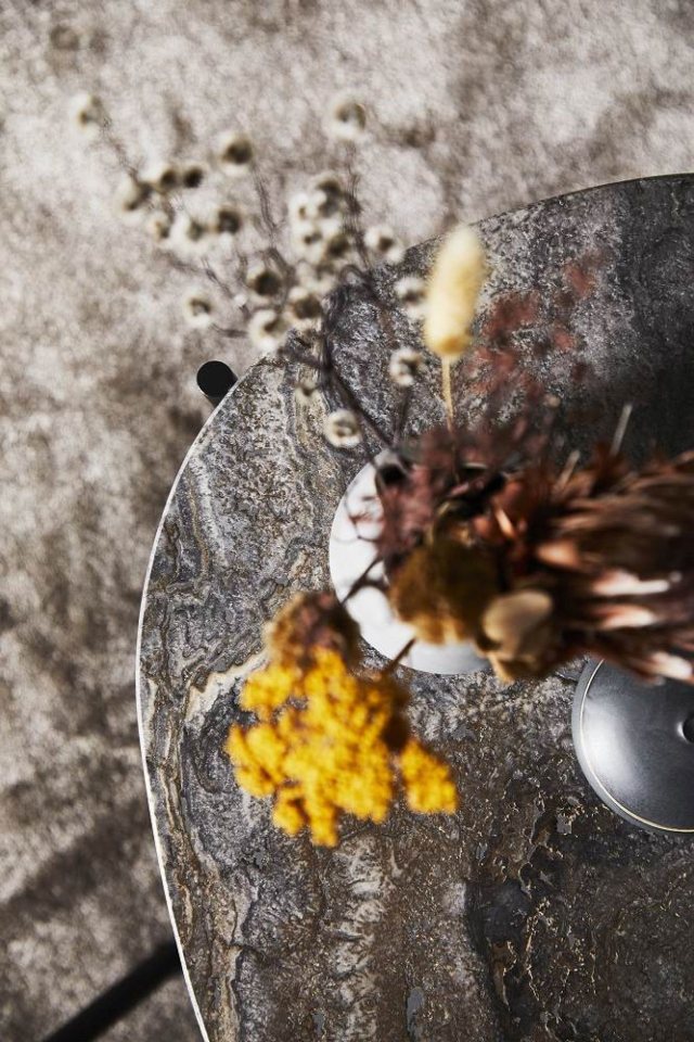 Nahaufnahme des La Terra Couchtischs von Woud in Grau Melange mit dekorativen Trockenblumen.