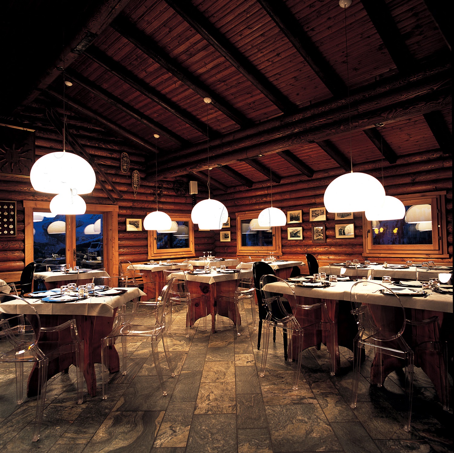 Innenaufnahme eines Restaurants mit mehreren weißen Fly Pendelleuchten von Kartell über den Tischen.