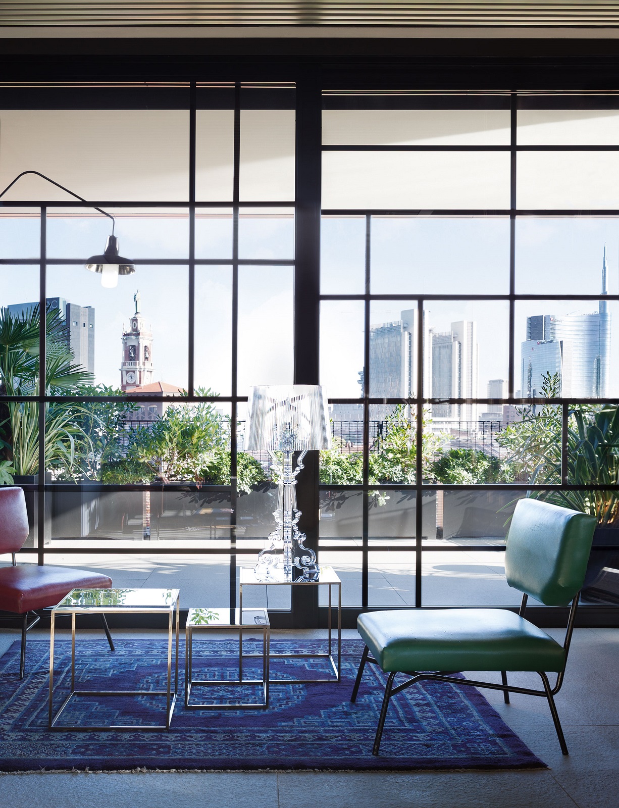 Glasklare Bourgie Tischleuchte von Kartell auf einem Beistelltisch vor einem Fenster mit Stadtblick.