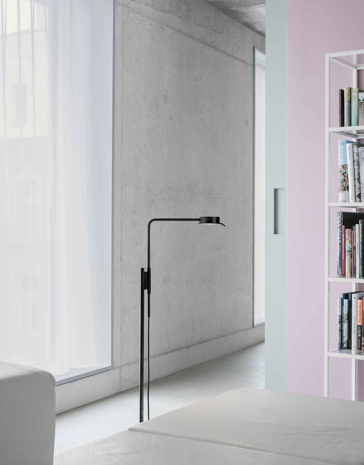Schwarze w102 F Chipperfield Stehleuchte von wästberg im modernen Wohnzimmer mit Betonwand und Bücherregal.