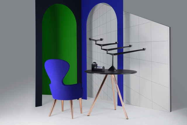 Schwarzer Tom Dixon Spin Kerzenständer auf rundem Tisch mit Kupferbeinen, neben blauem Sessel und farbigen Wänden.