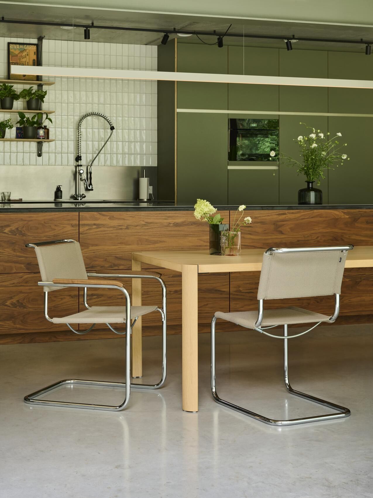 Zwei Thonet S 33 Freischwinger Stühle mit beigem Stoffbezug und verchromtem Stahlrohrgestell an Esstisch.