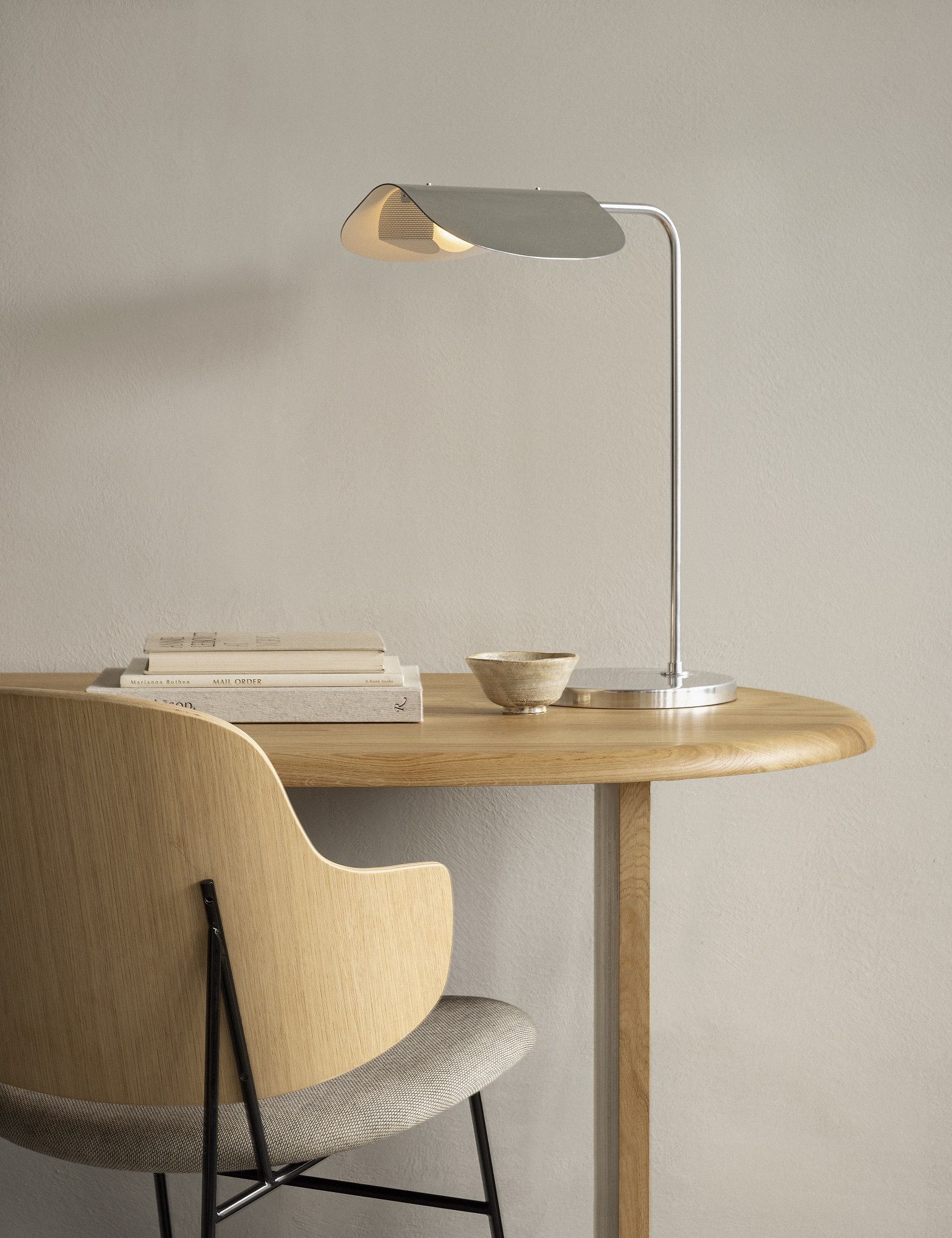 Audo Copenhagen Eclipse Schreibtischlampe aus Metall auf einem runden Holzschreibtisch mit Stuhl.