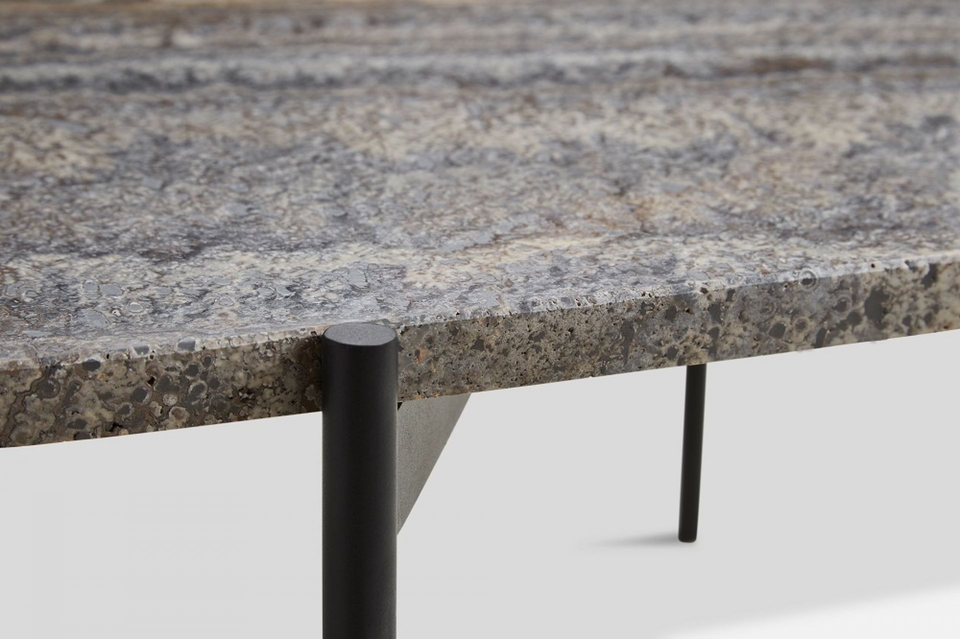 Detailansicht des La Terra Couchtisches von Woud mit melierter, grauer Tischplatte und schwarzen Metallbeinen.