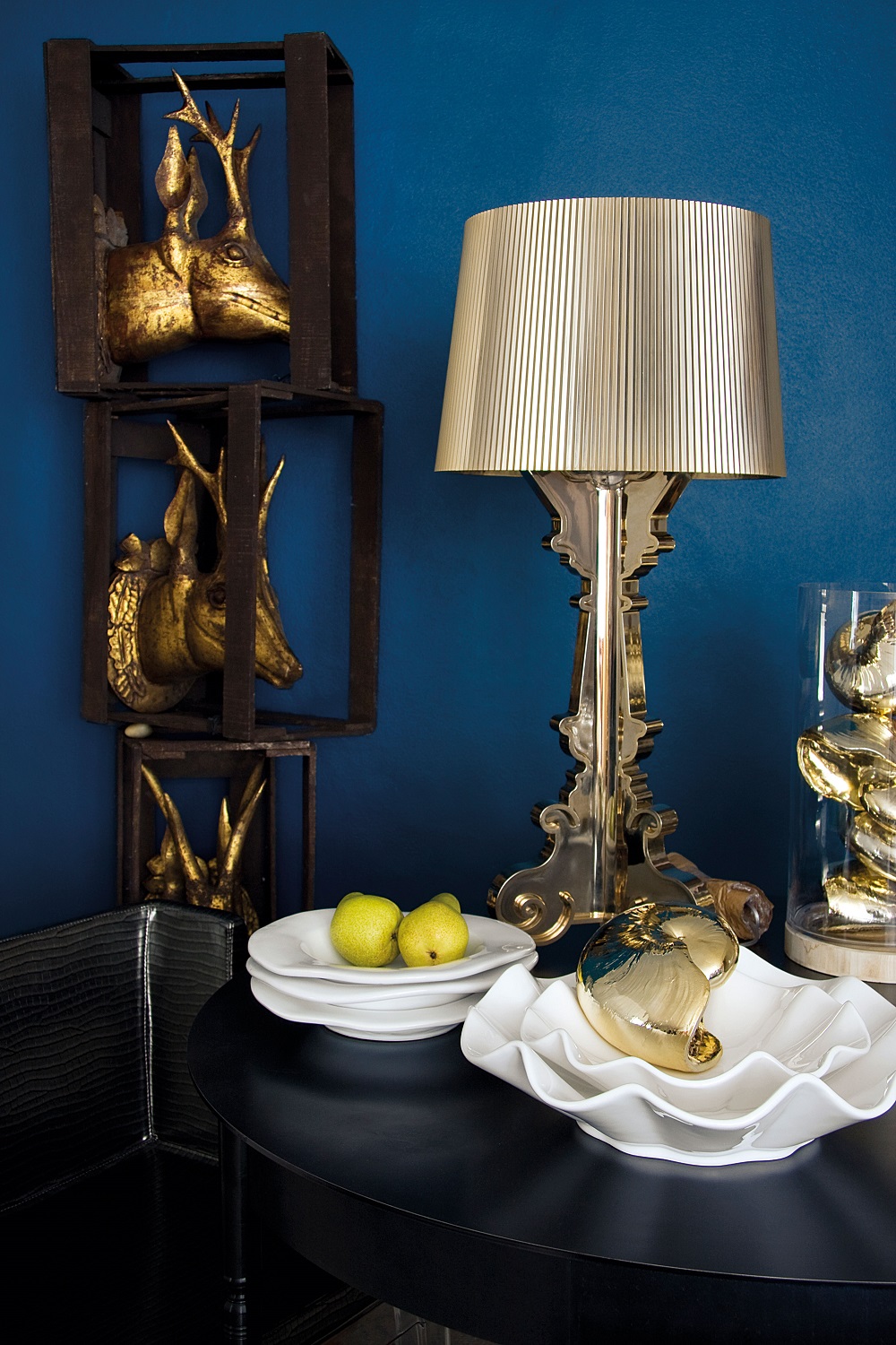 Nahaufnahme der goldenen Kartell Bourgie Tischleuchte auf einem schwarzen Tisch mit Dekoration.