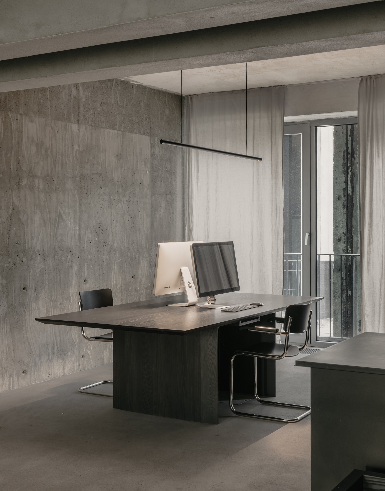 Moderne Büroeinrichtung mit w181 S2 Linier Pro Pendelleuchte von wästberg über dunklem Holztisch und Bürostühlen.