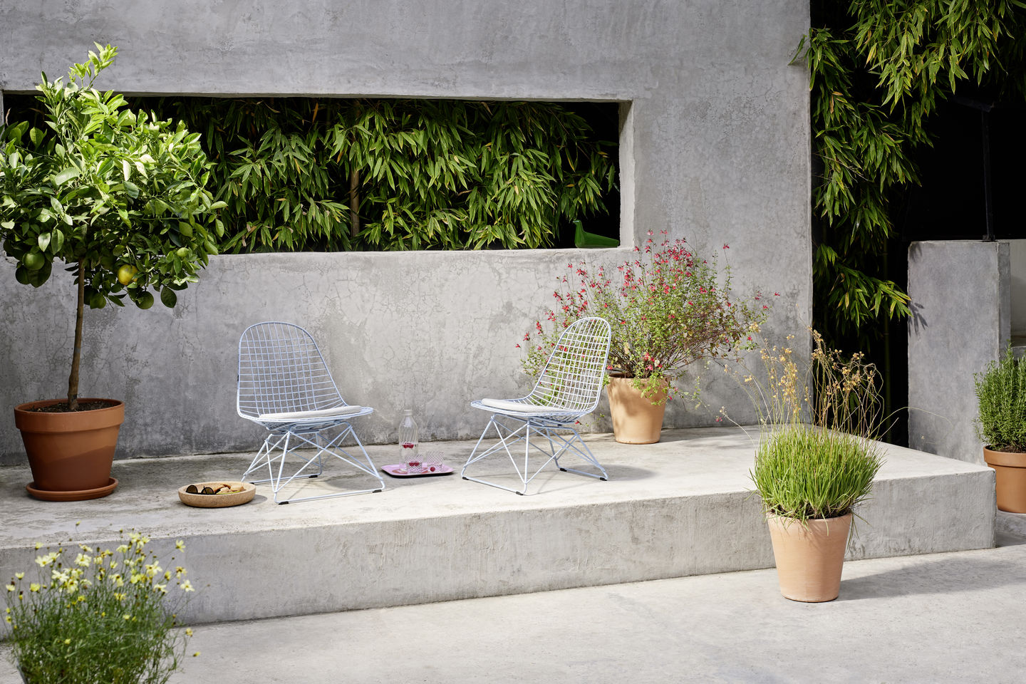 Zwei Vitra LKR-2 Wire Chairs mit Sitzbezug im Garten, minimalistisches Design, komfortable Sitzgelegenheit.