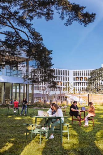 Menschen nutzen grüne Bolder 3-Sitzer Tische von Fermob im Freien, ideal für Büro, Garten oder Terrasse.