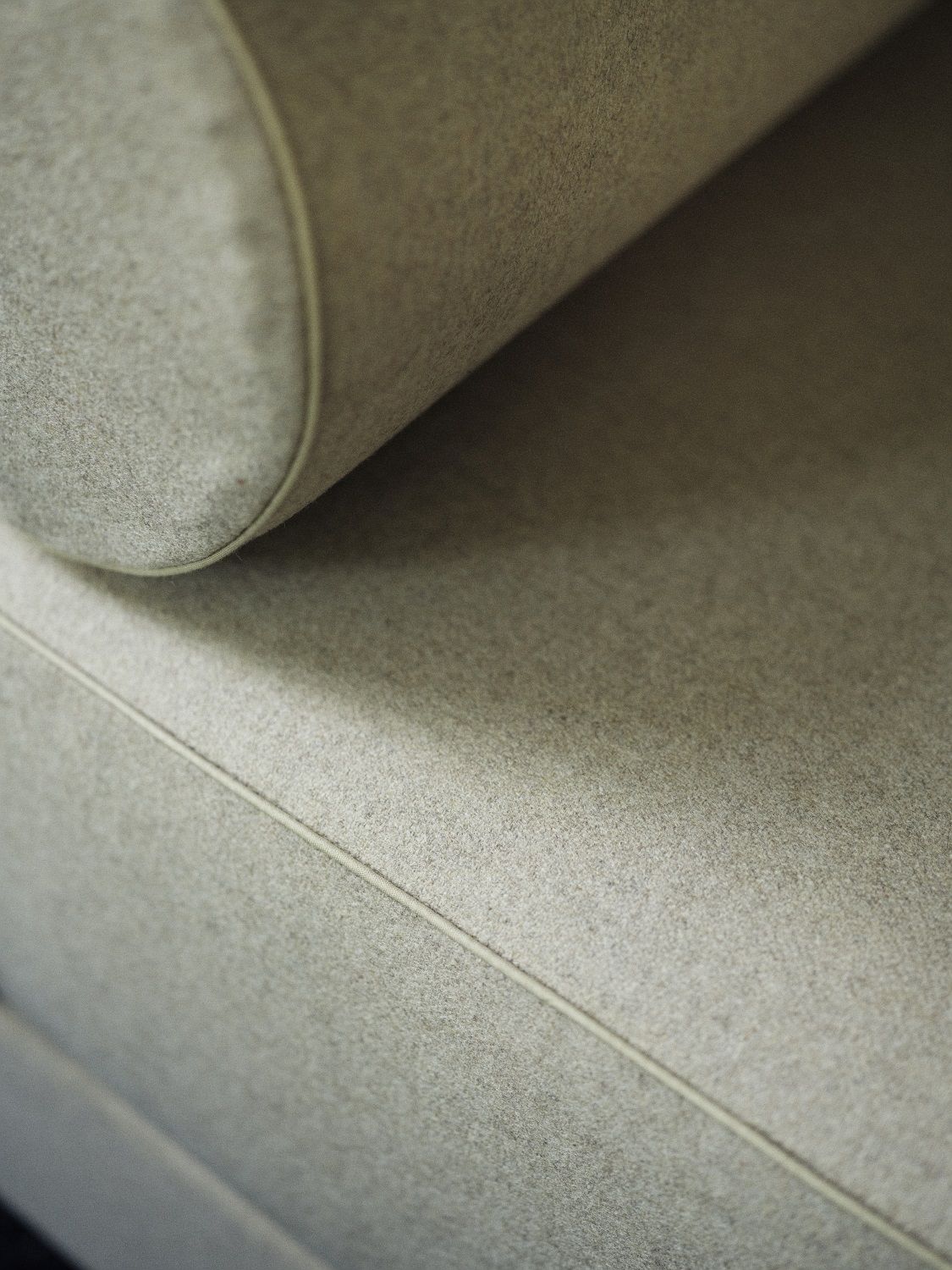 Detailaufnahme des Lubi Daybeds: Hochwertige, graue Stoffoberfläche mit feiner Naht und gerolltem Kopfteil.