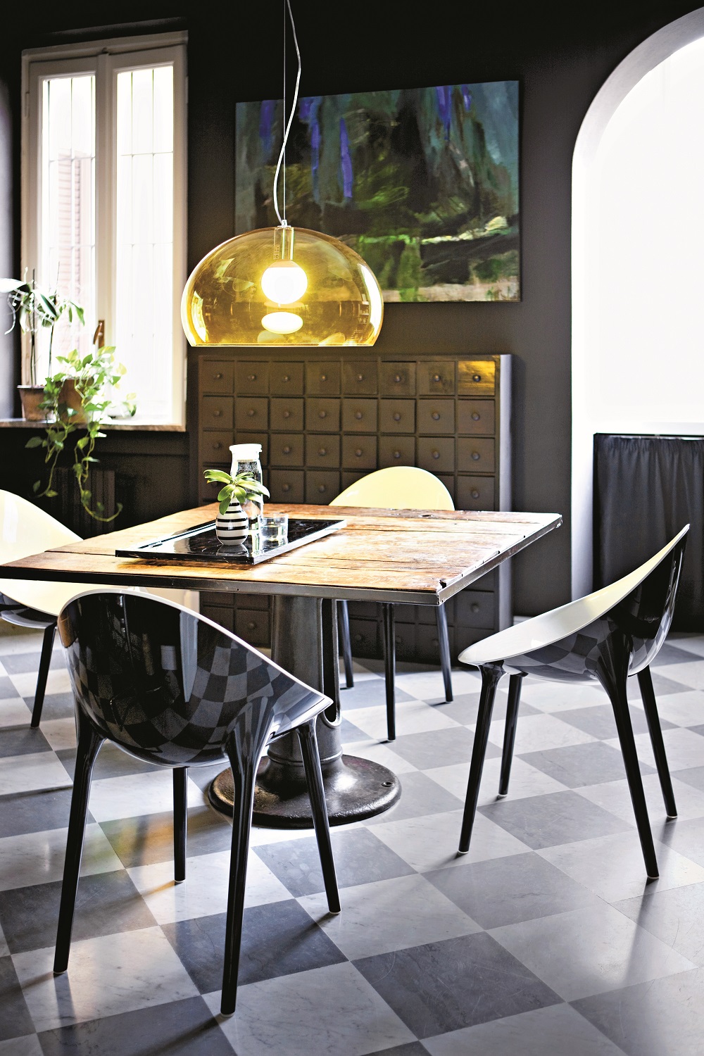 Esszimmer mit Kartell Big Fly Pendelleuchte in Gelb über Holztisch und Designstühlen.