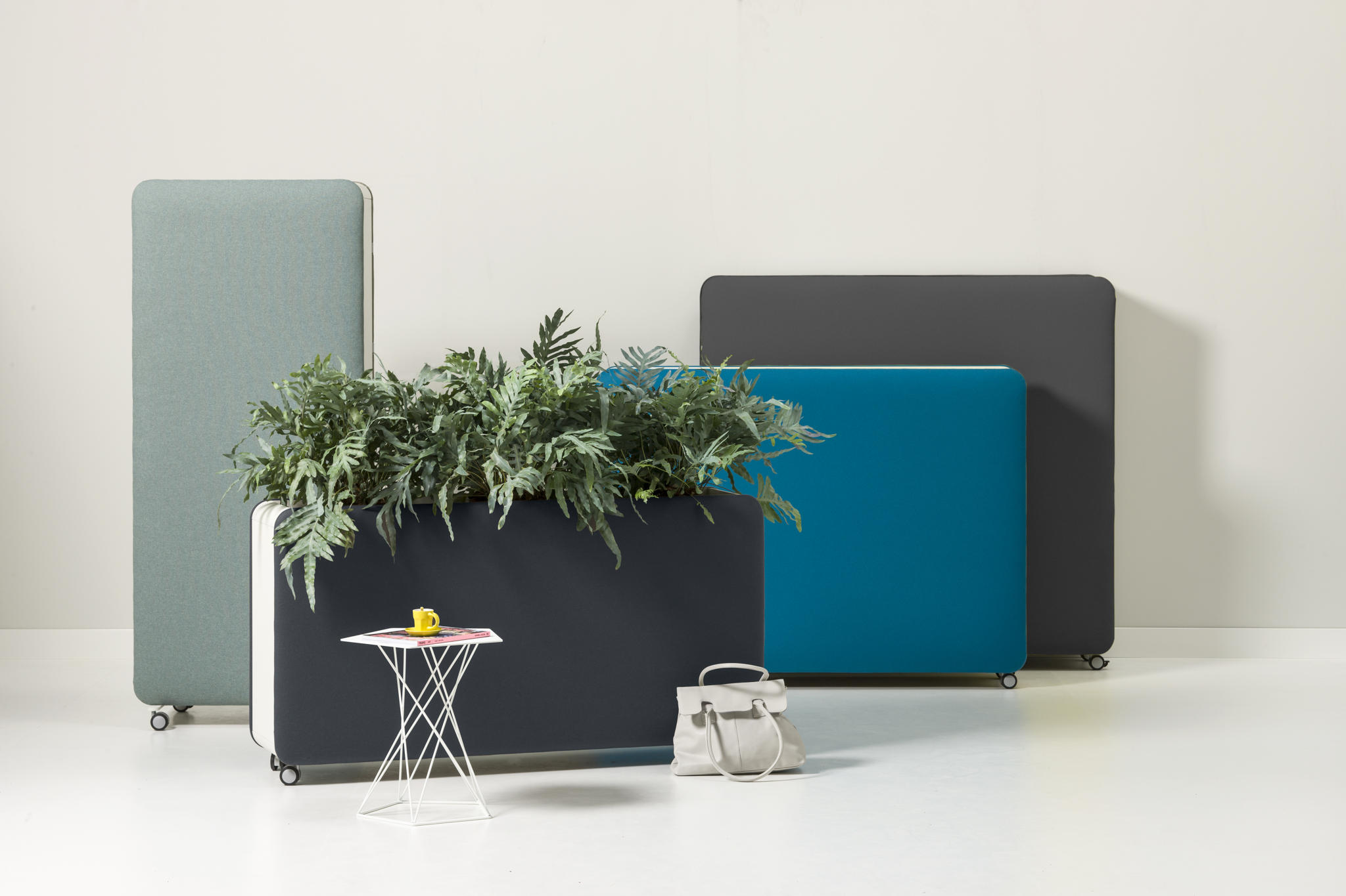 Cascando Pillow Space Akustik-Raumteiler in verschiedenen Farben mit Pflanzen, Tisch und Tasche im modernen Büro.