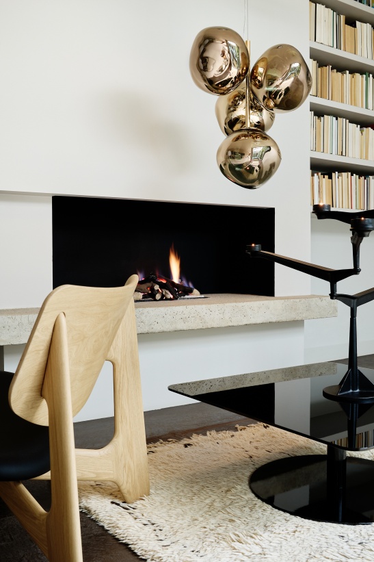 Nahaufnahme eines Wohnzimmers mit Tom Dixon Spin Kerzenständer, Kamin und moderner Einrichtung.