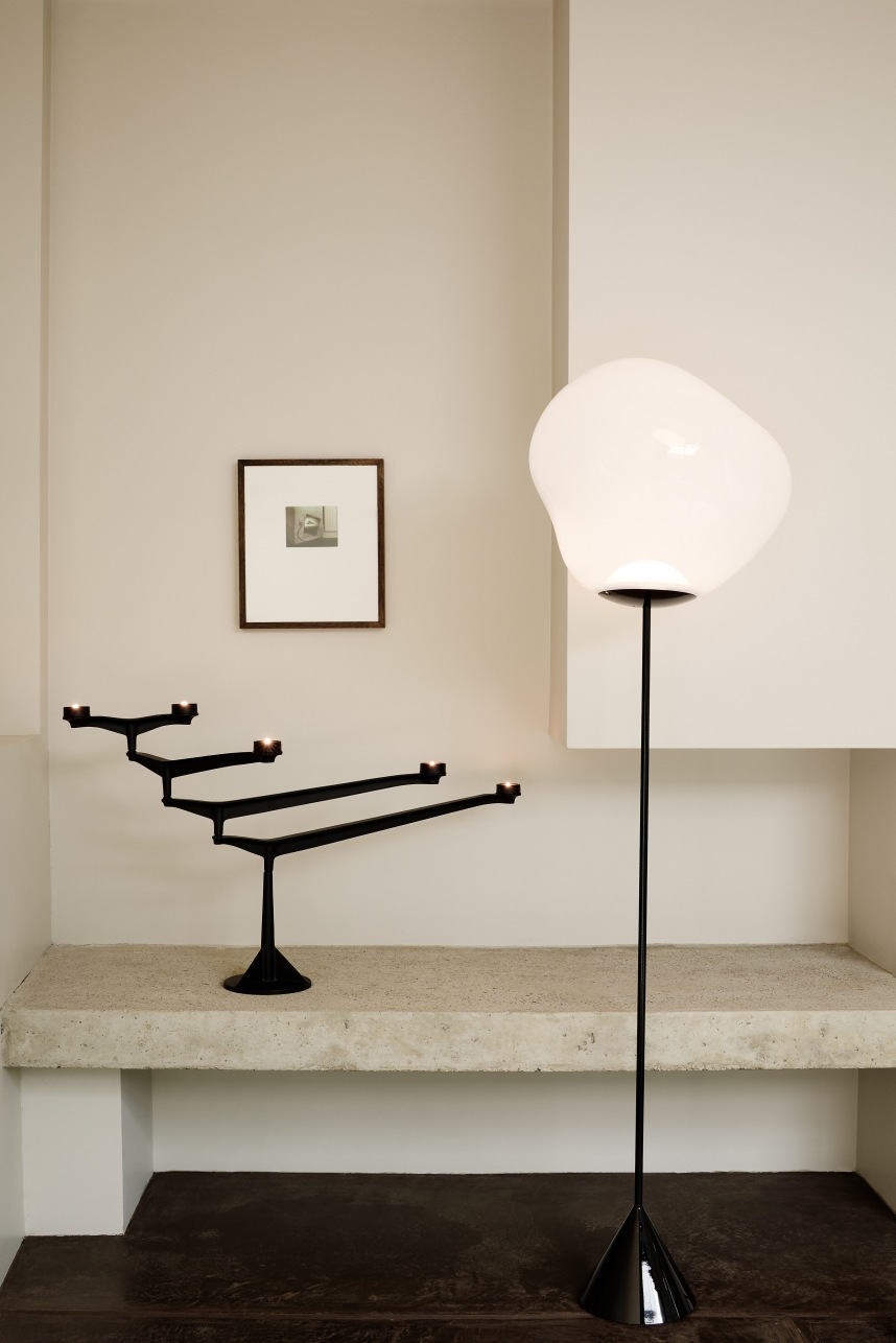 Schwarzer Spin Kerzenständer von Tom Dixon auf einem Betonsims, neben einer modernen Stehlampe in minimalistischem Interieur.