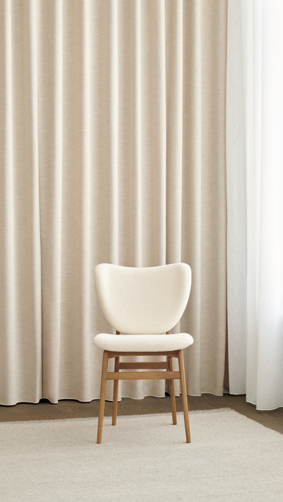 NORR11 Elephant Dining Chair, frontgepolstert, mit hellem Bouclé-Bezug und Holzbeinen vor beigen Vorhängen.