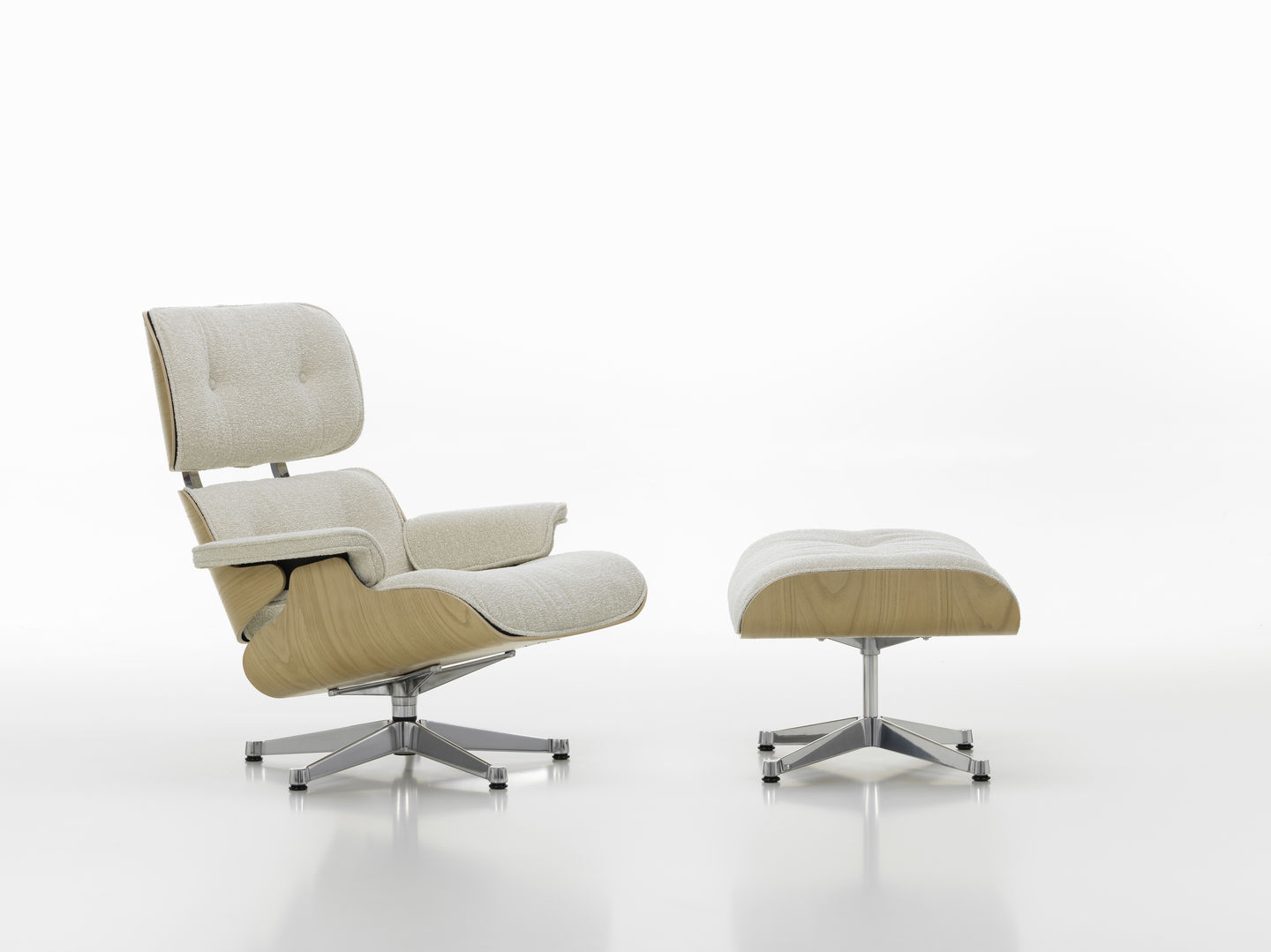 Vitra Eames Lounge Chair mit Ottoman in hellem Stoffbezug und Holzschale auf weißem Hintergrund.