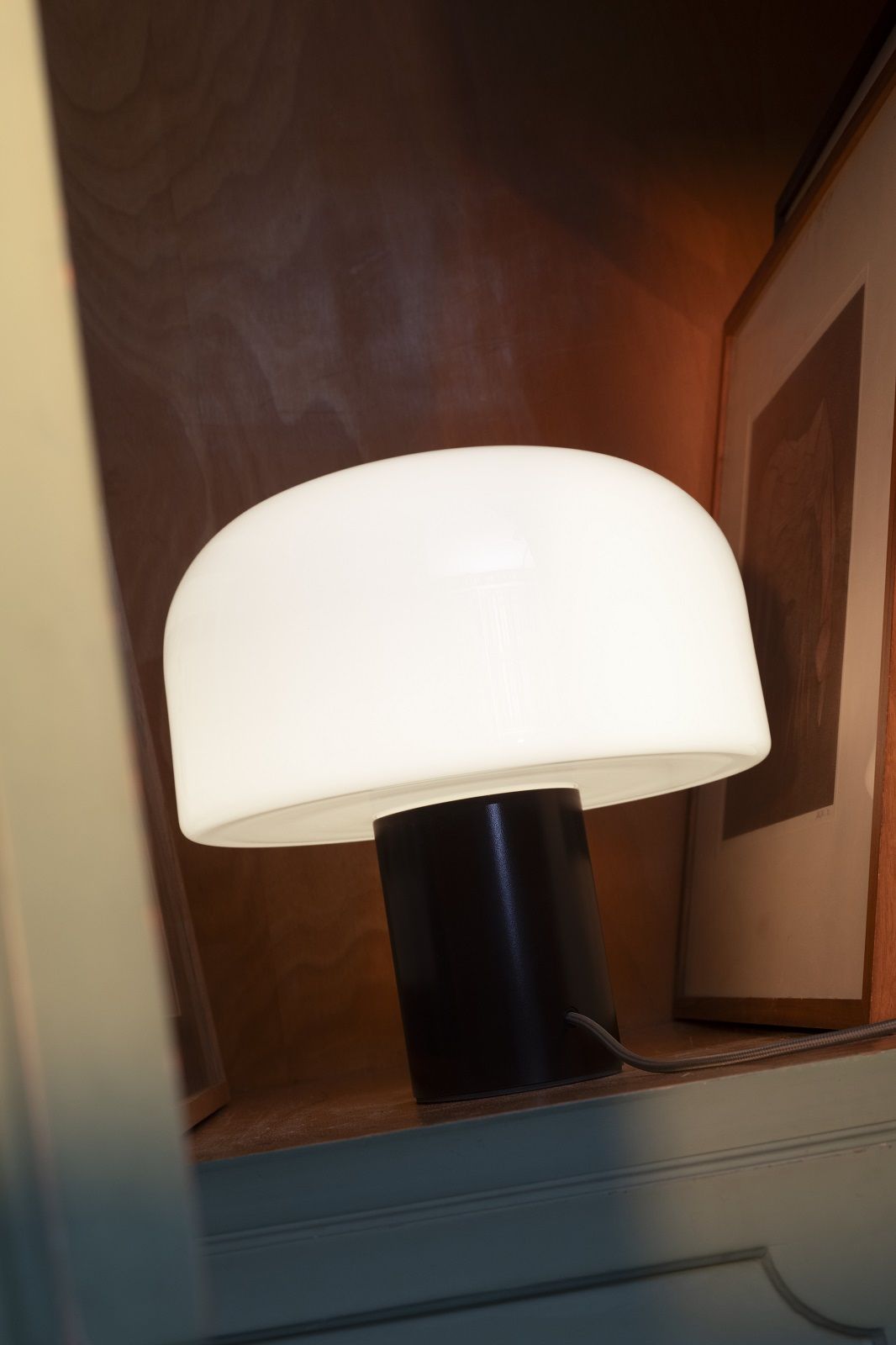 Nahaufnahme der modernen Flos Bellhop Tischleuchte mit weißem Glasschirm und dunklem Sockel.