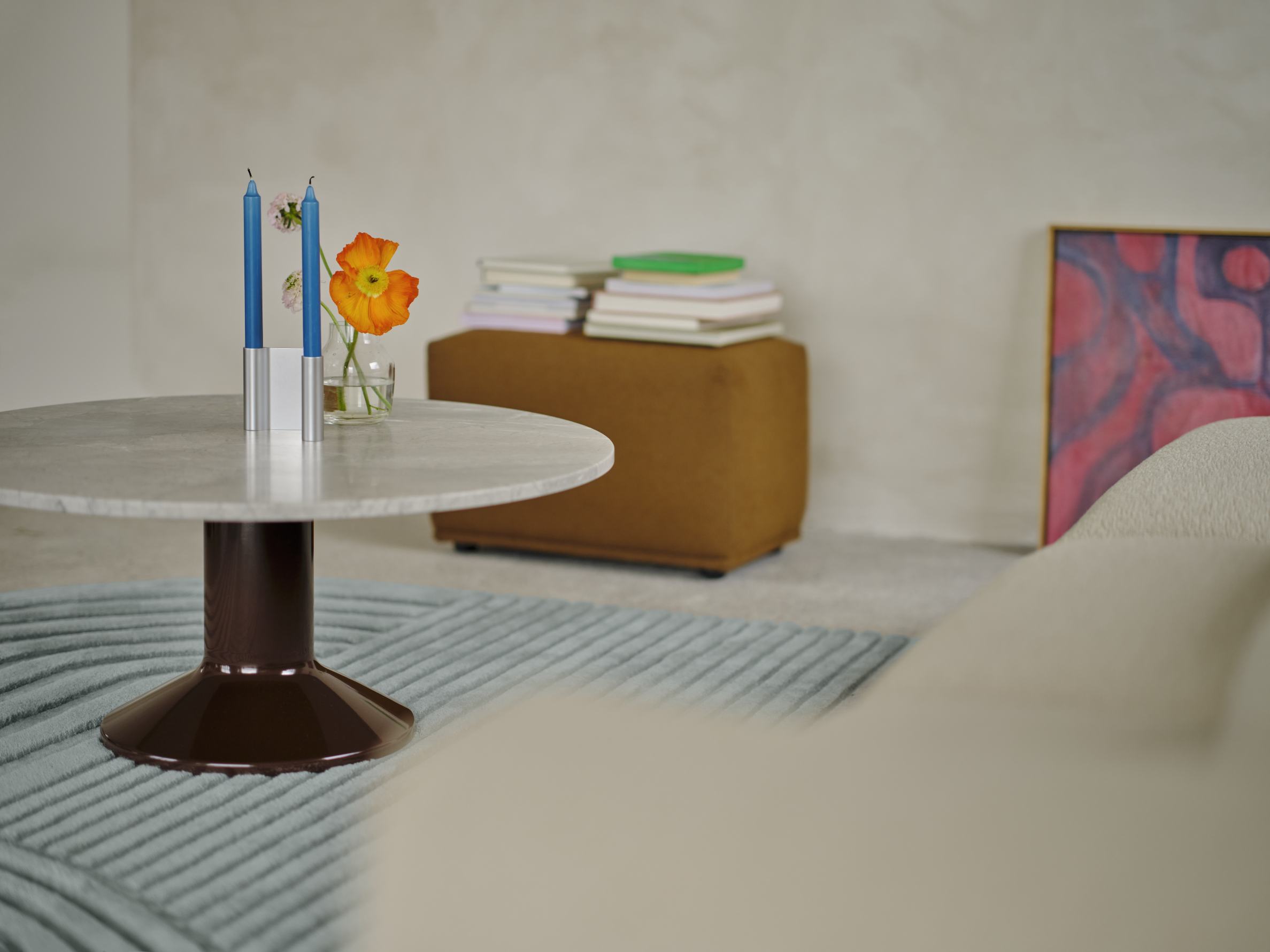 Muuto MIDST Coffee Table: Runder Couchtisch mit Marmorplatte, braunem Fuß, Kerzen und Blumen im Wohnzimmer.
