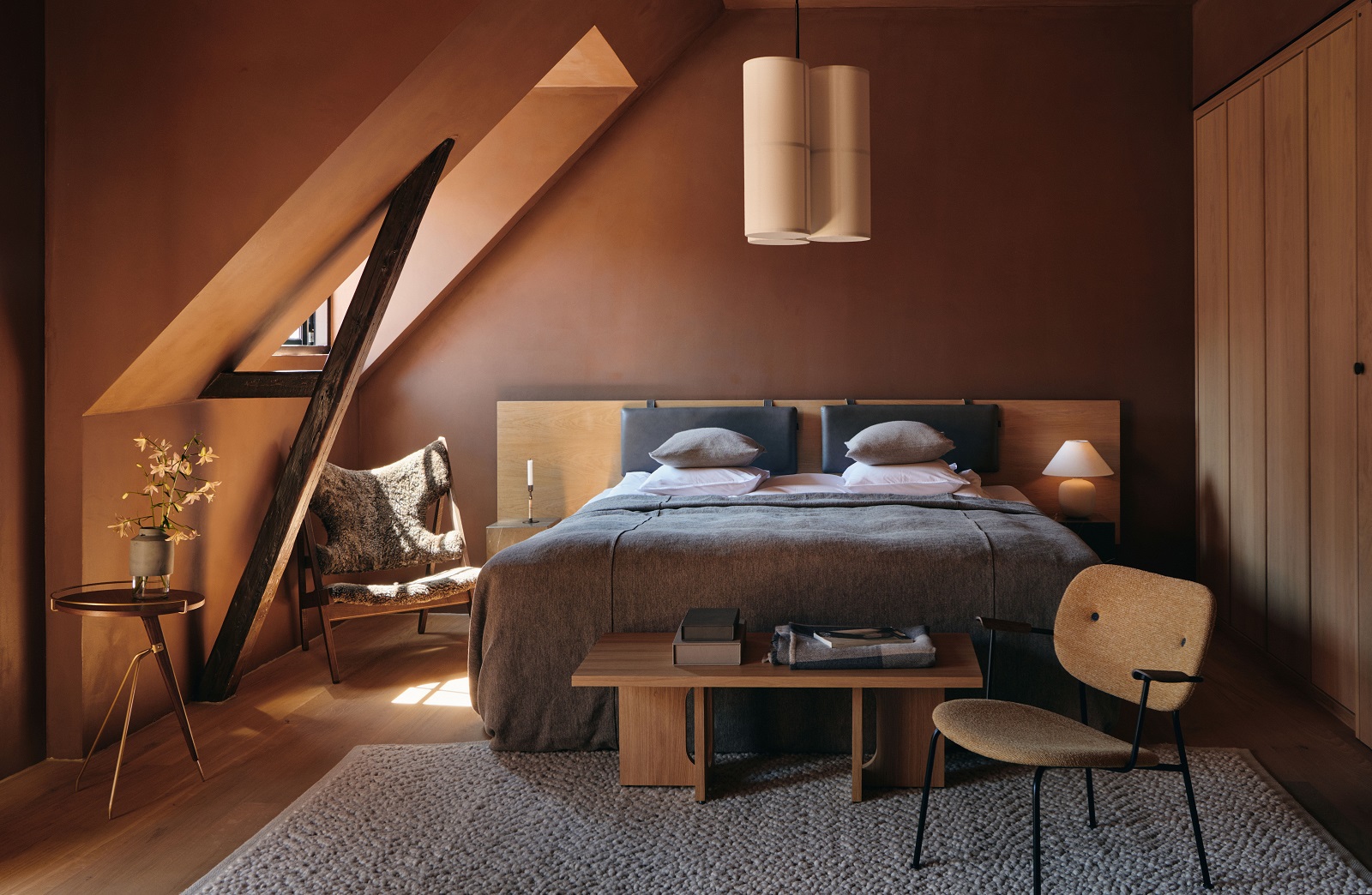 Audo Copenhagen Gravel Rug Teppich in einem Schlafzimmer mit Bett und Möbeln.