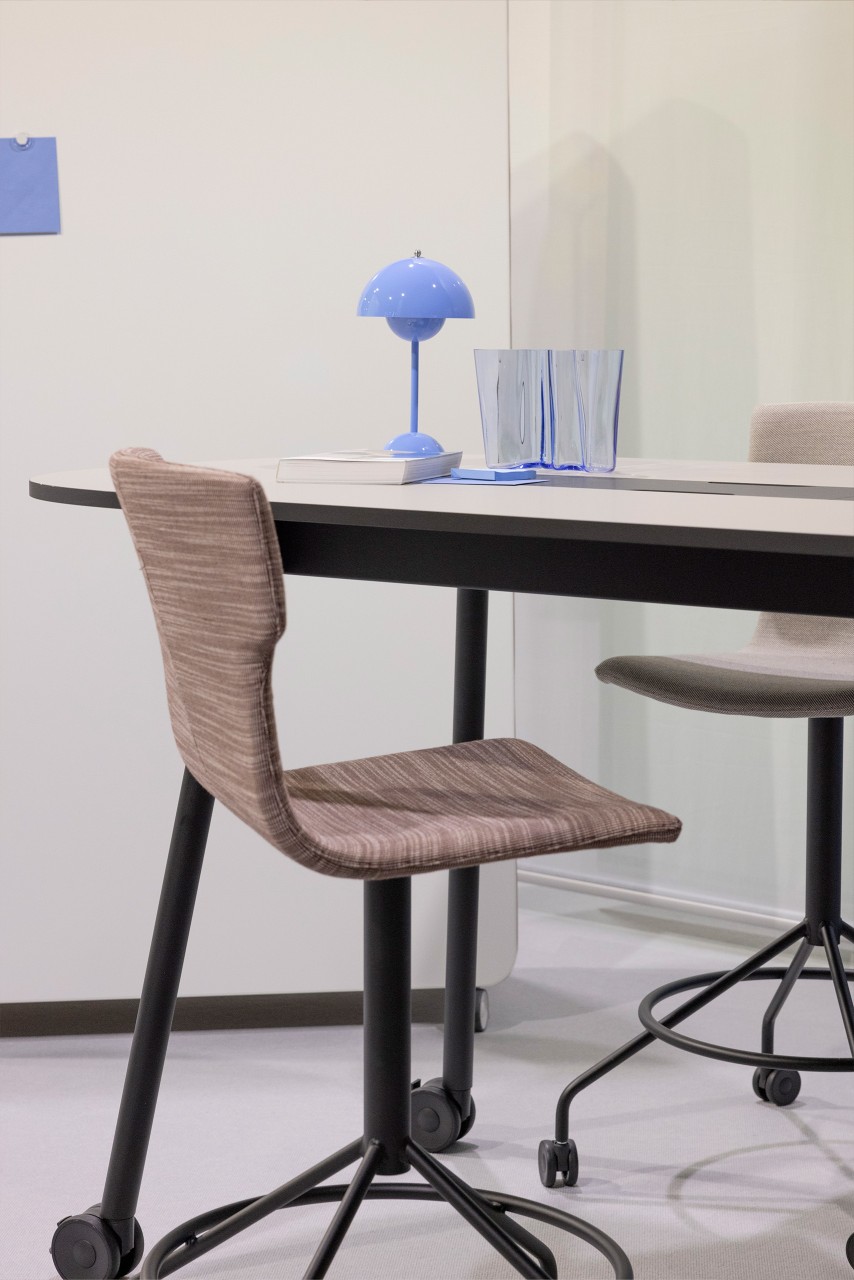 Cascando Co-Chair Bürodrehstuhl mit braunem Stoffbezug und schwarzen Rollen vor einem Schreibtisch.
