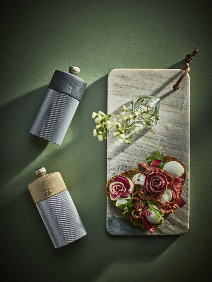 Produktfoto: Peugeot Line Pfeffermühle H 12 cm in Graphit und Carbon neben Brotzeit auf Marmorbrett.