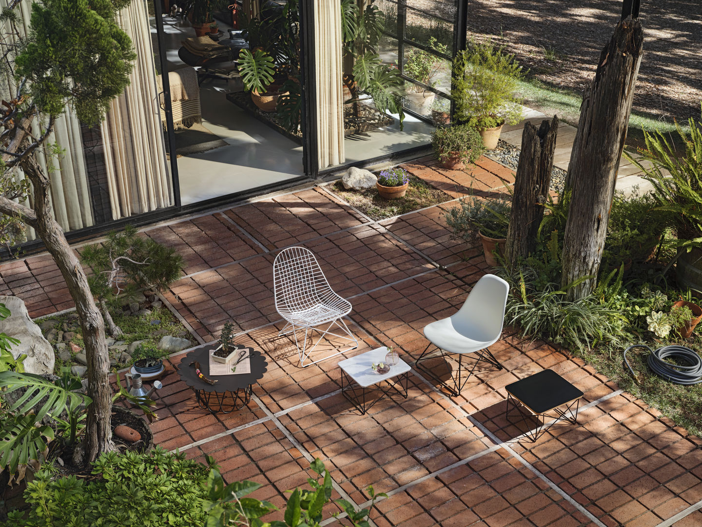 Draufsicht: LKR-2 Wire Chair Stuhl von Vitra und ein weißer Kunststoffstuhl im Garten.
