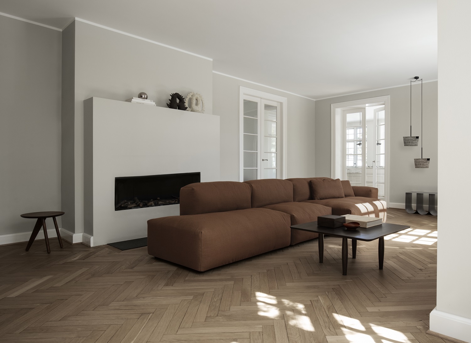Fin Side Table Beistelltisch von Norr11 aus dunklem Holz neben braunem Sofa im Wohnzimmer.