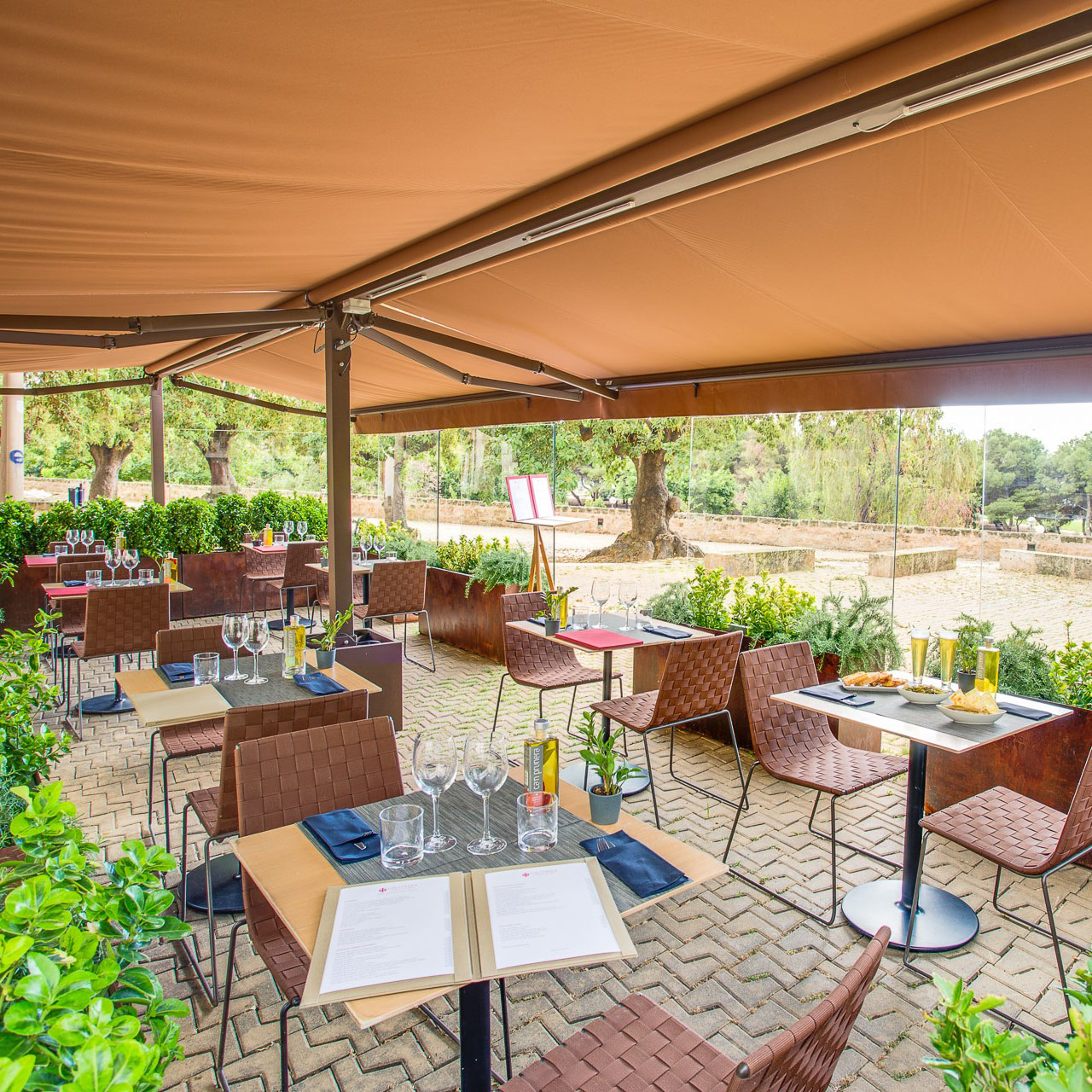 Außenbereich eines Restaurants mit mehreren Trenza Stühlen von Andreu World mit braunem Webmuster.
