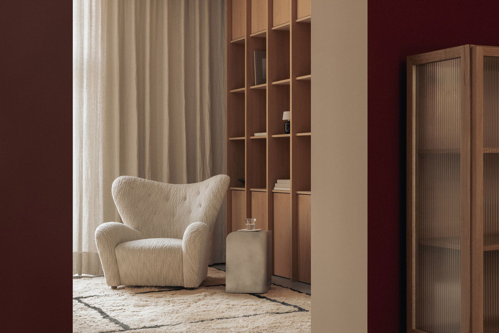 Audo Copenhagen Curiosity Cabinet Holzschrank und Sessel in beigem Wohnzimmer mit Teppich.