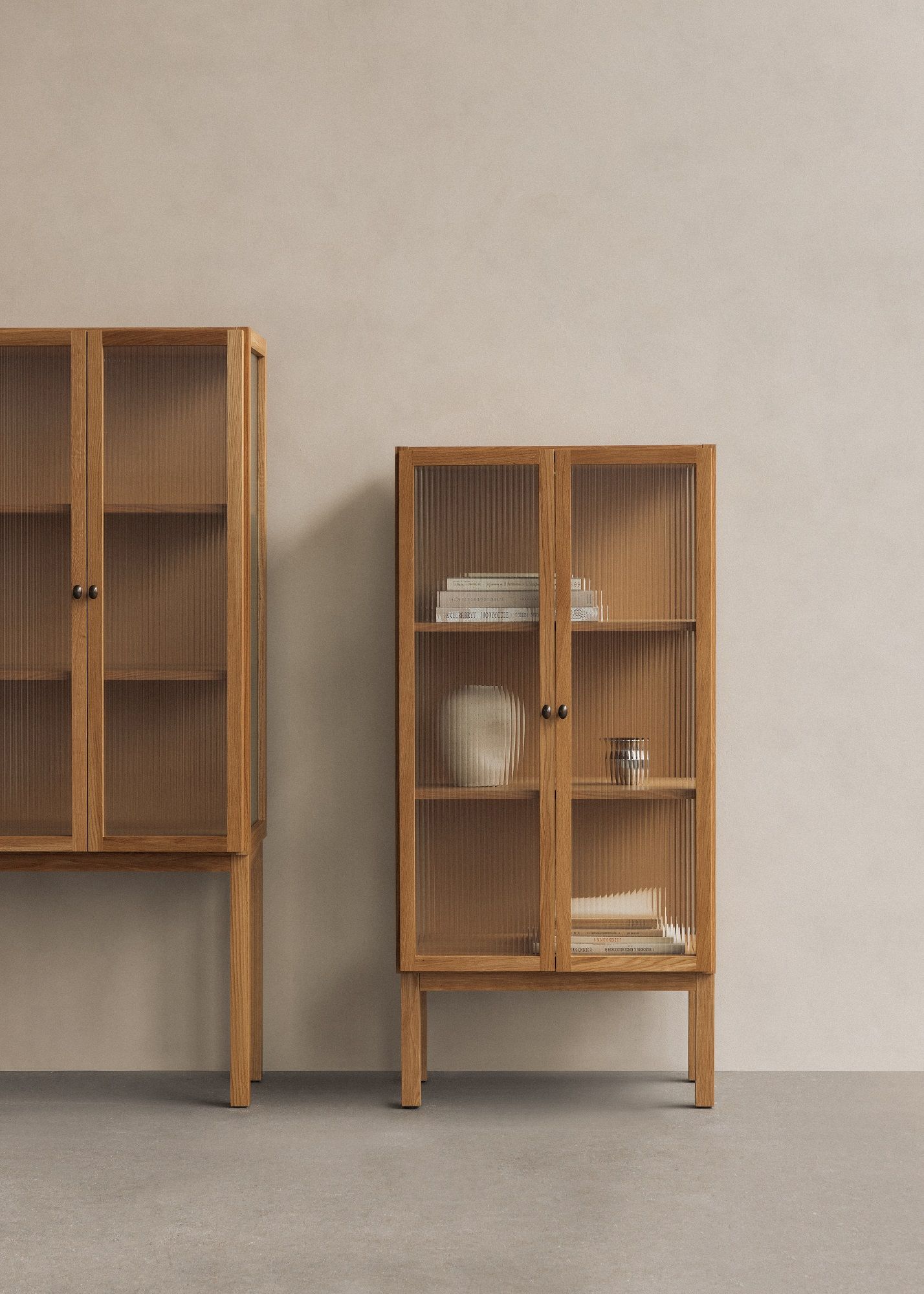 Audo Copenhagen Curiosity Cabinet: Zwei Holzschränke mit geriffeltem Glas, ideal für Wohnzimmer und Esszimmer.