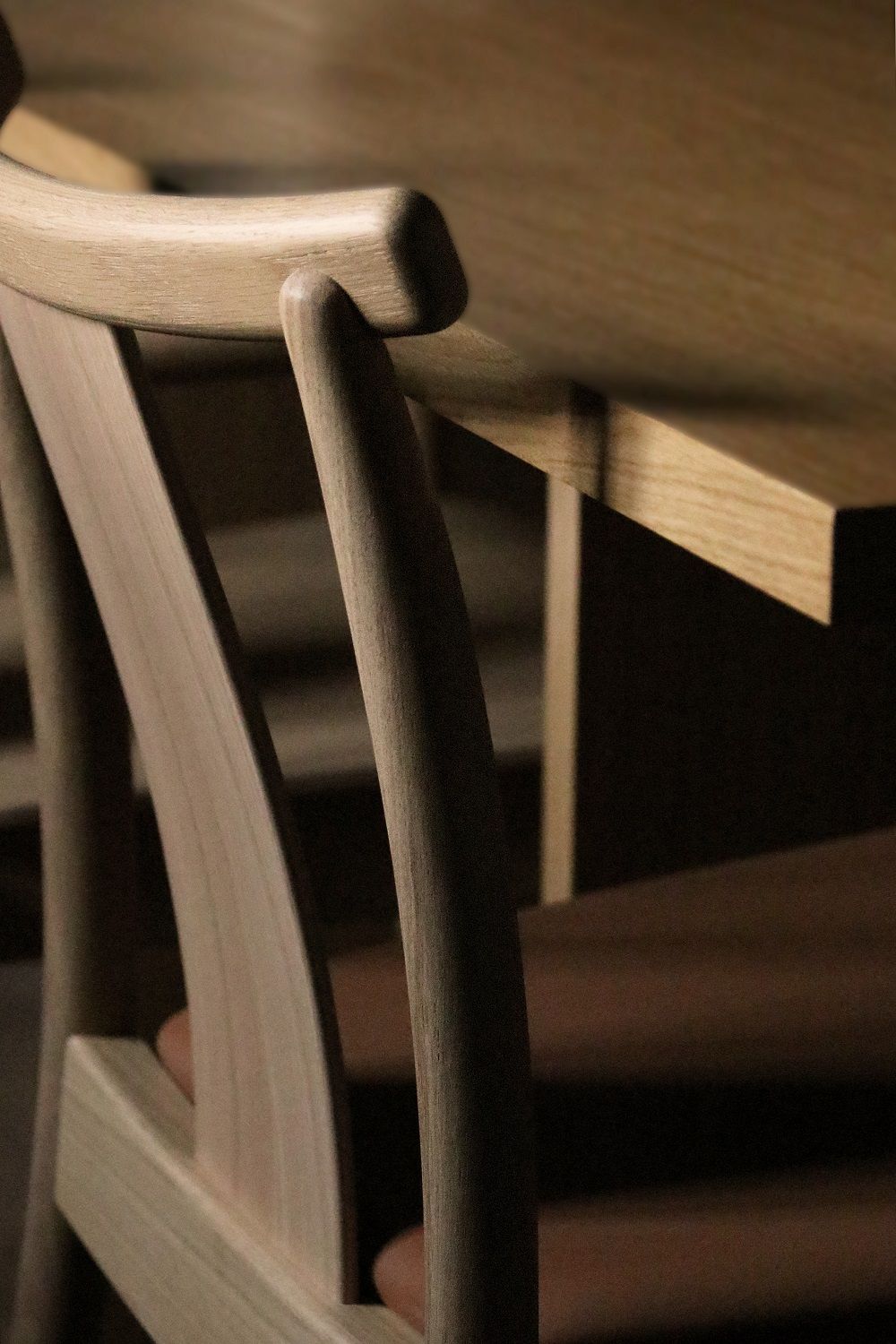 Detailaufnahme des Audo Copenhagen Merkur Dining Chair Stuhls aus hellem Holz am Esstisch.