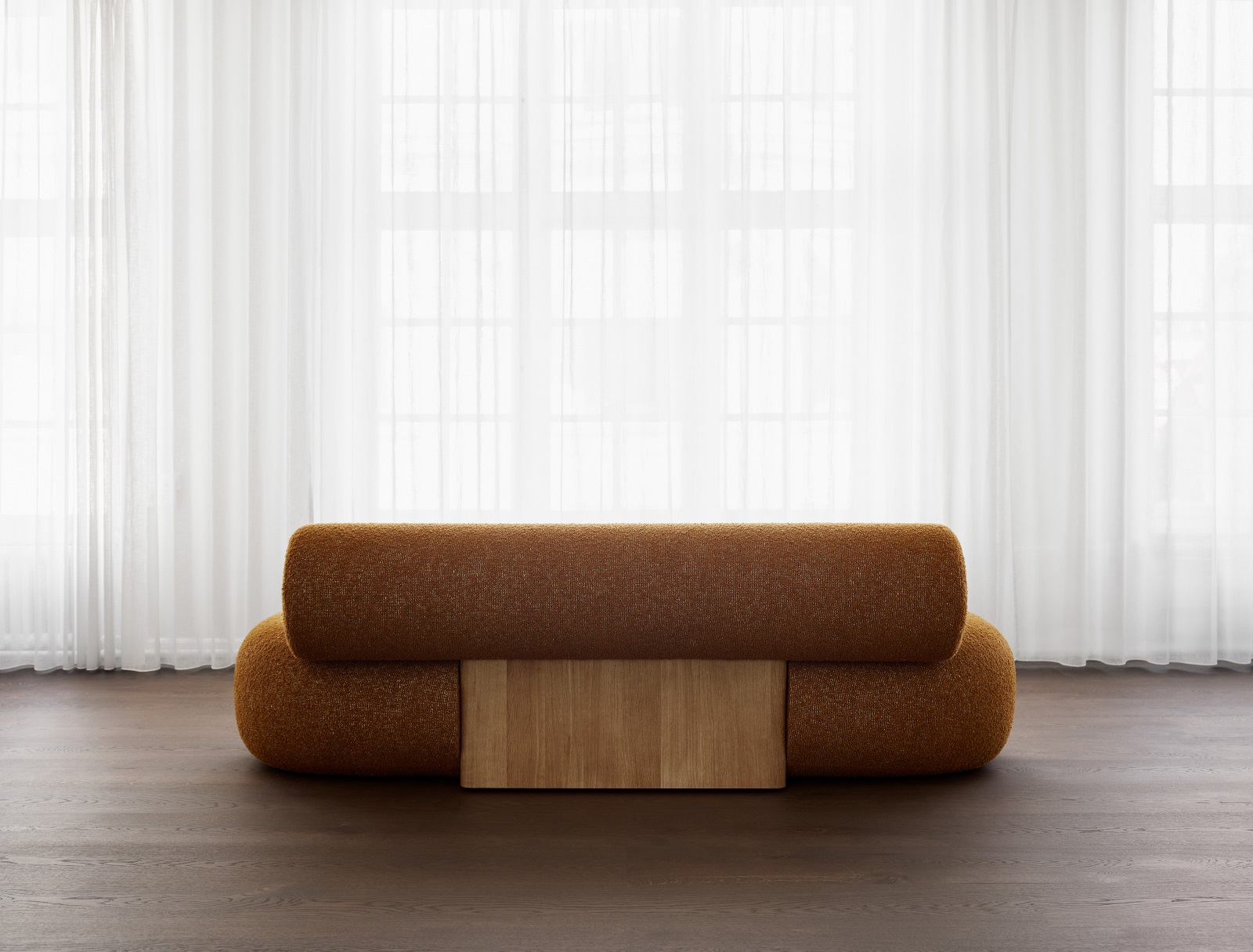 Hippo Sofa von Norr11 aus Holz mit braunem Bouclé-Stoff und hellem Holzsockel vor Fenster.