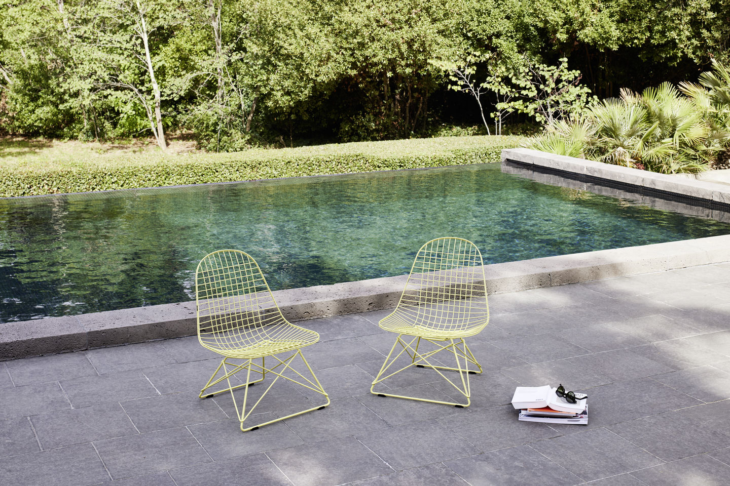 Zwei gelbe Vitra Wire Chairs LKR-2 mit Sitzbezug am Pool, moderne Gartenmöbel.