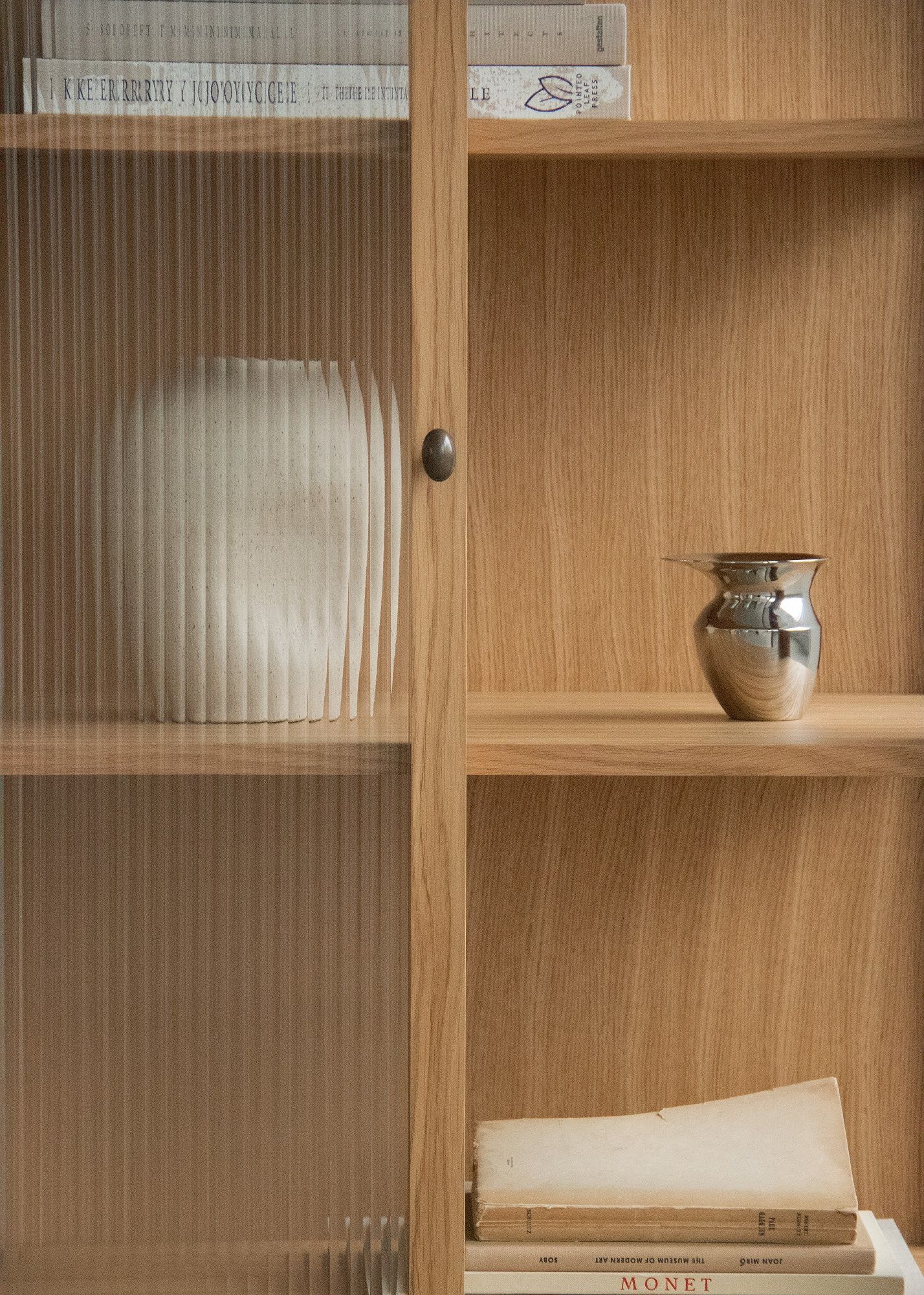 Detailaufnahme des Audo Copenhagen Curiosity Cabinet Schranks aus Eiche mit Glasfront, Innenraum mit Deko.