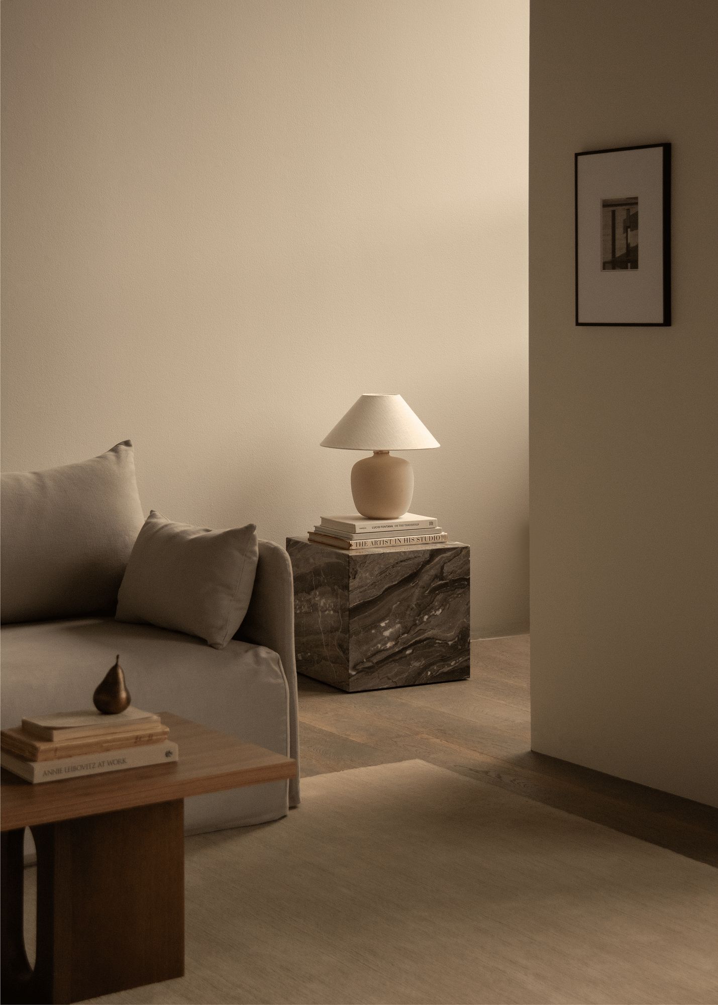 Beige Offset Sofa von Audo Copenhagen mit Couchtisch, Lampe und Dekoration in einem stilvollen Wohnzimmer.