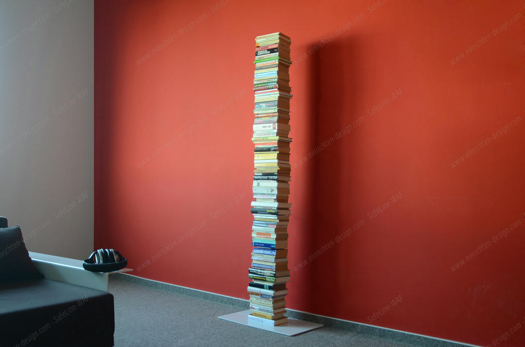 Booksbaum Standregal: Freistehendes Bücherregal aus gestapelten Büchern vor roter Wand. Dekoratives Bücherregal.