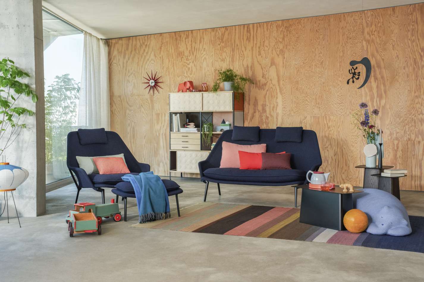 Vitra Slow Chair Sessel mit Ottoman und Stoffbezug in stilvollem Wohnzimmerambiente.