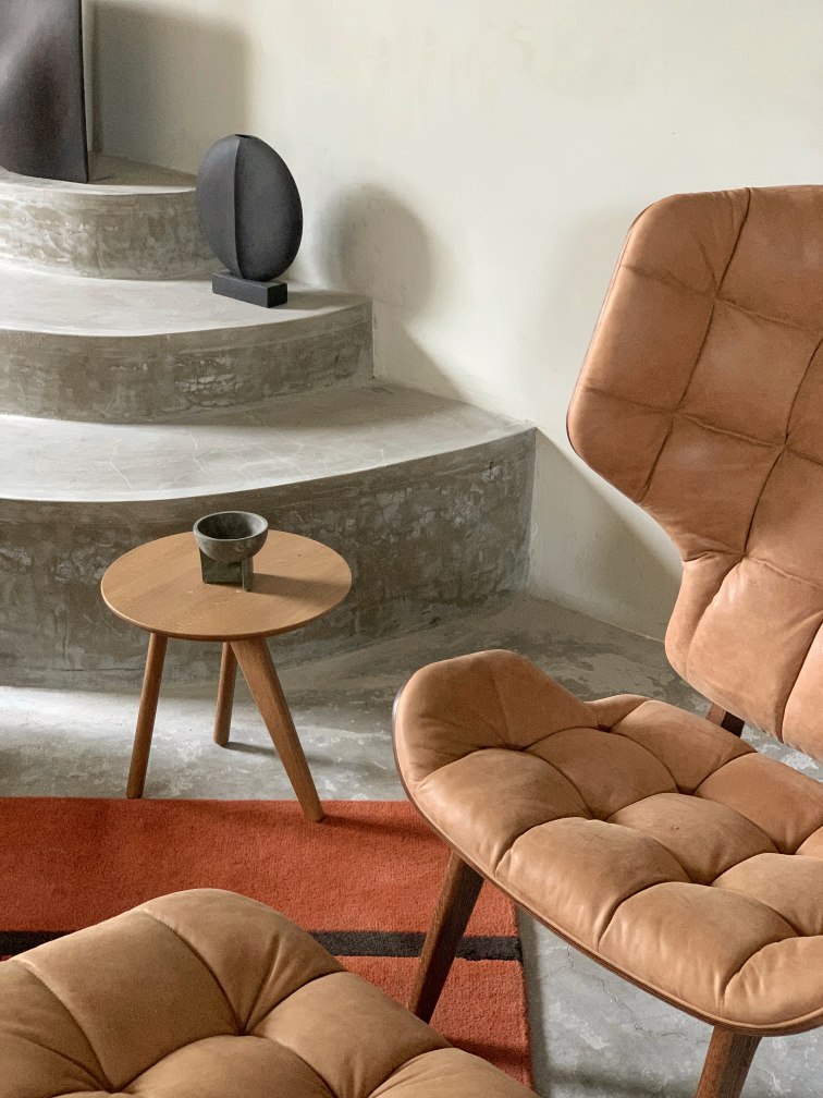 NORR11 Mammoth Chair Sessel aus braunem Leder mit Steppung und passendem Hocker auf Teppich.