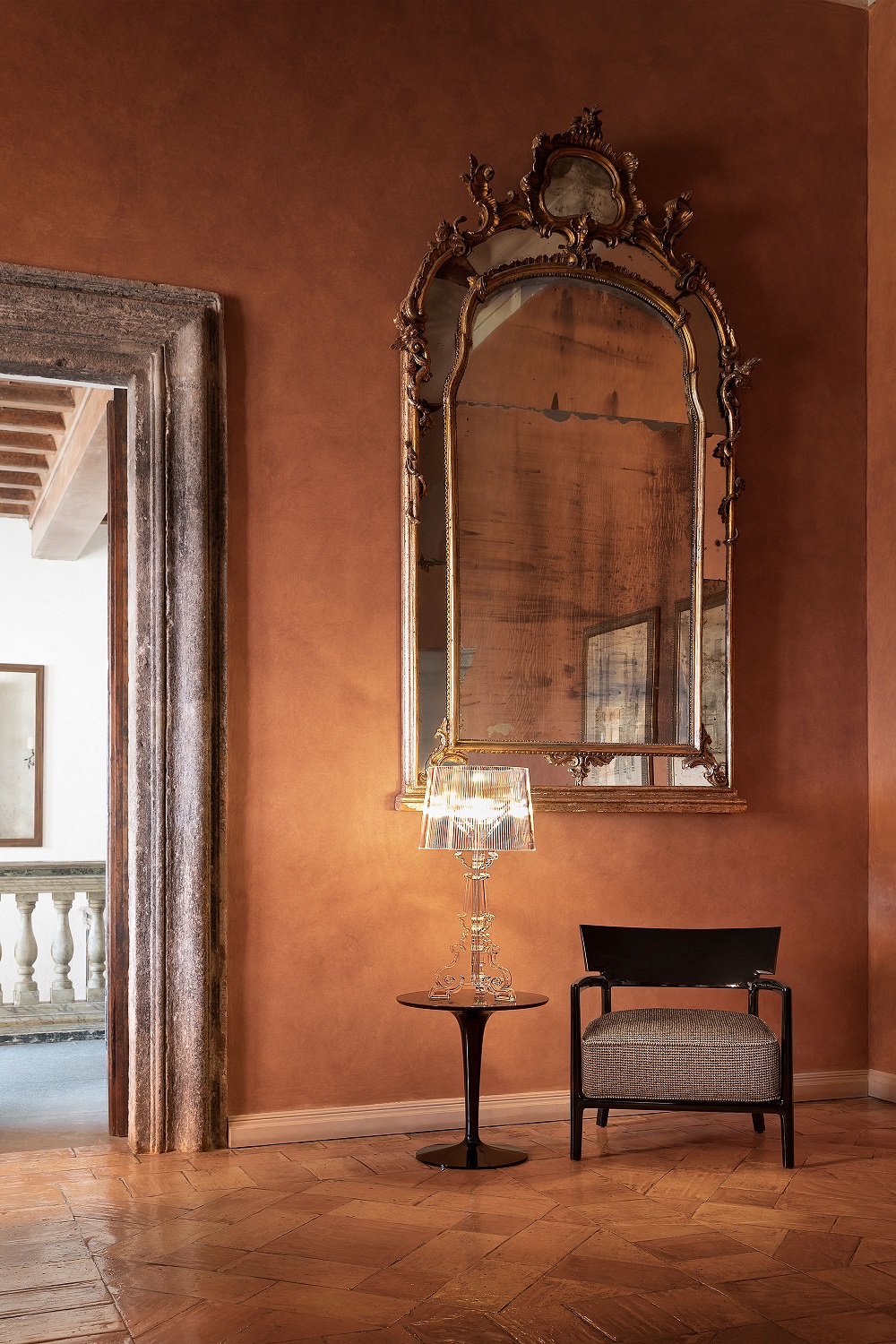 Bourgie Tischleuchte von Kartell, glasklar und dimmbar, auf einem Beistelltisch in einem eleganten Interieur.